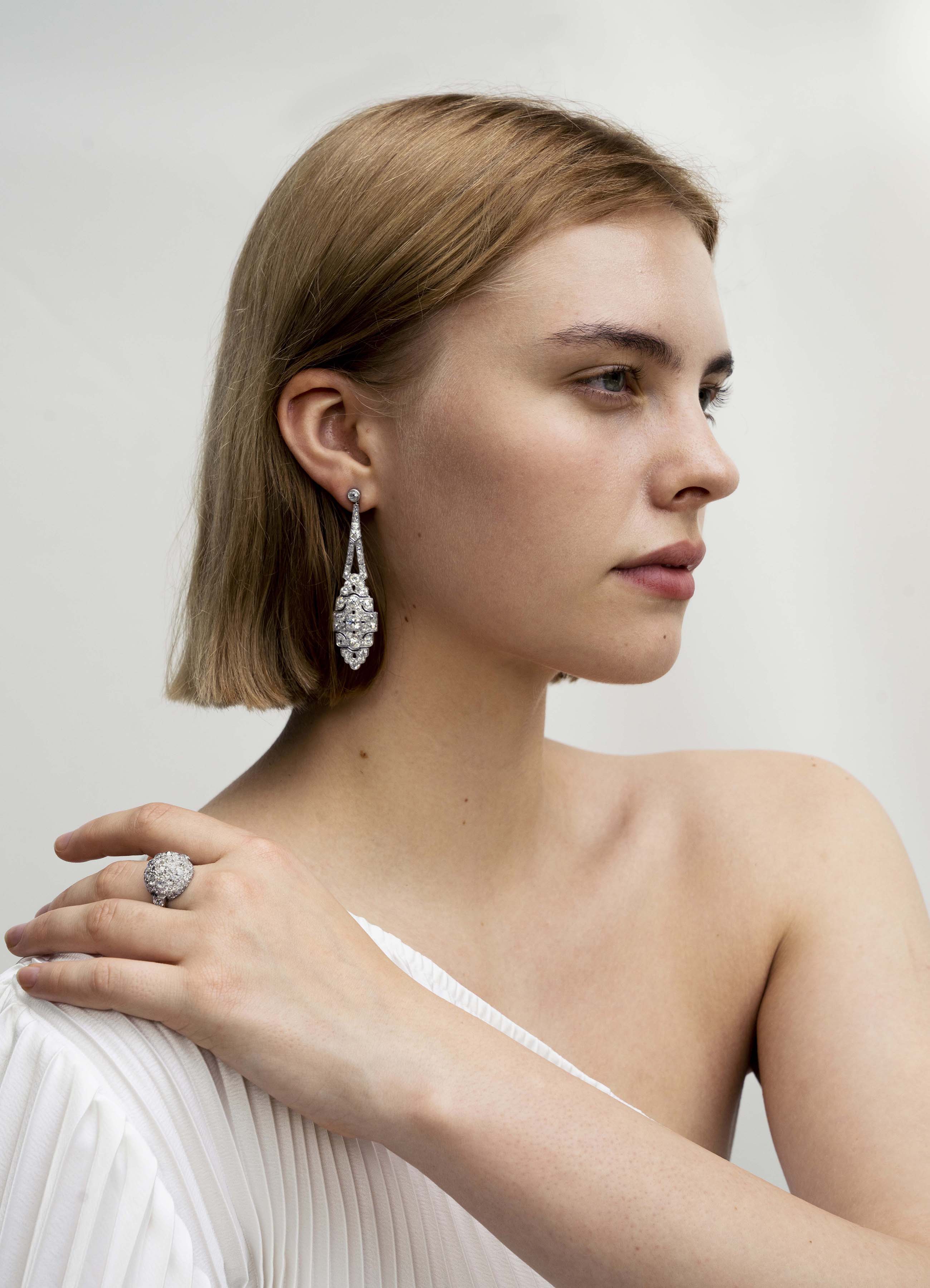 Art Deco Diamond Drop Earrings. A mixture of old mine cut and old European cut diamonds are set in intricate platinum settings. The stones are estimated to weigh approximately 9 carats in total weight. The high-quality stones are estimated to range from F to G in color and VS to SI in quality. America, circa 1920. On a model.