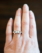 This seven stone ring was inspired by a 17th century diamond ring that we once had. The arrangement is characteristic of rings that date from 1650-1700. We modernized the look with six Asscher cut diamonds surrounding an emerald cut diamond. This ring features a GIA certified 2.05 carat emerald cut diamond, E color and VVS1 clarity. There are six Asscher cut diamonds, approximately .79 carats in total diamond weight, F color, and VS1/VS2 clarity.It was handcrafted in our 18k old gold. On a model's hand.