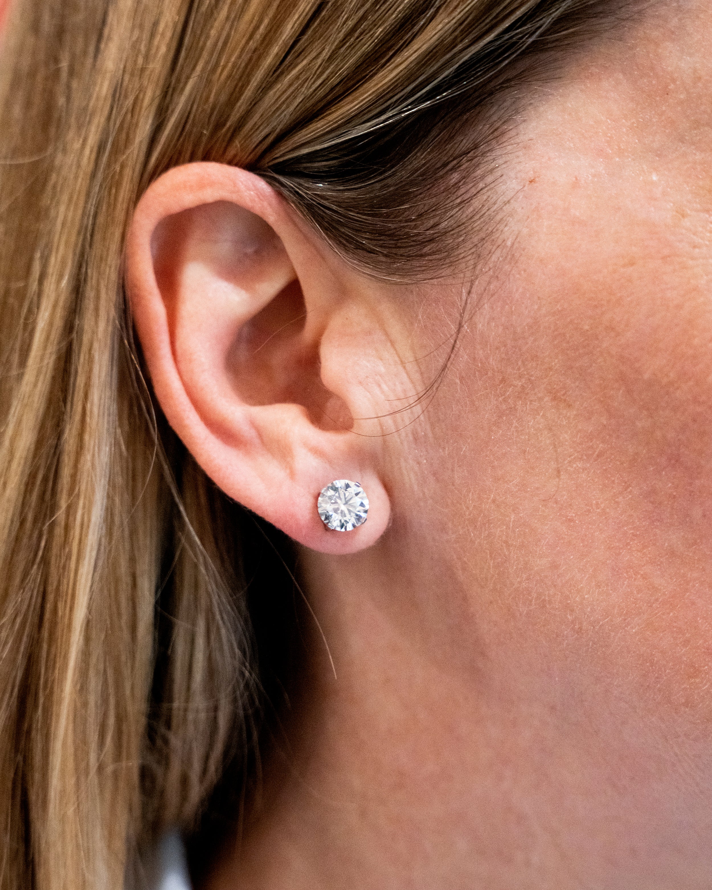 Classic round brilliant cut diamond earring studs. Handmade platinum four-tab prong settings with locking backs. Featuring two GIA certified diamonds, 2.01 carats J color and SI1 clarity and 2.01 I color and SI1 clarity. Over four carats in total weight. Front view of the diamond earrings. Diamonds being worn on the ear lob.