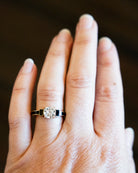 Inspired by Victorian Era black jewelry, we designed this unique ring with enamel details. The prongs are hand-filed to precise points and the traditional vitreous enamel is meticulously applied to the sides and shoulders of the ring. This ring features an old mine cut diamond of 1.52 carats, I color. Handcrafted in our 18k old gold. The ring being modeled on a hand to show the scale.