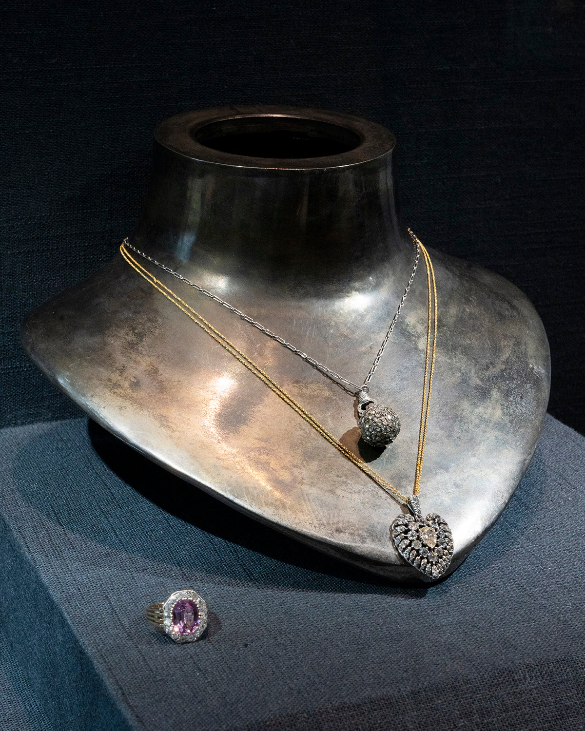 A rare Georgian-era diamond ball pendant is hanging on an early 20th century French platinum chain. Rose-cut diamonds are intricately pavé set in silver, gold, and platinum. The chain has French hallmarks and The ball is English in origin. Circa 1820. View of the necklace on a neck form displayed in a case layered with a diamond pendant necklace and a ring.