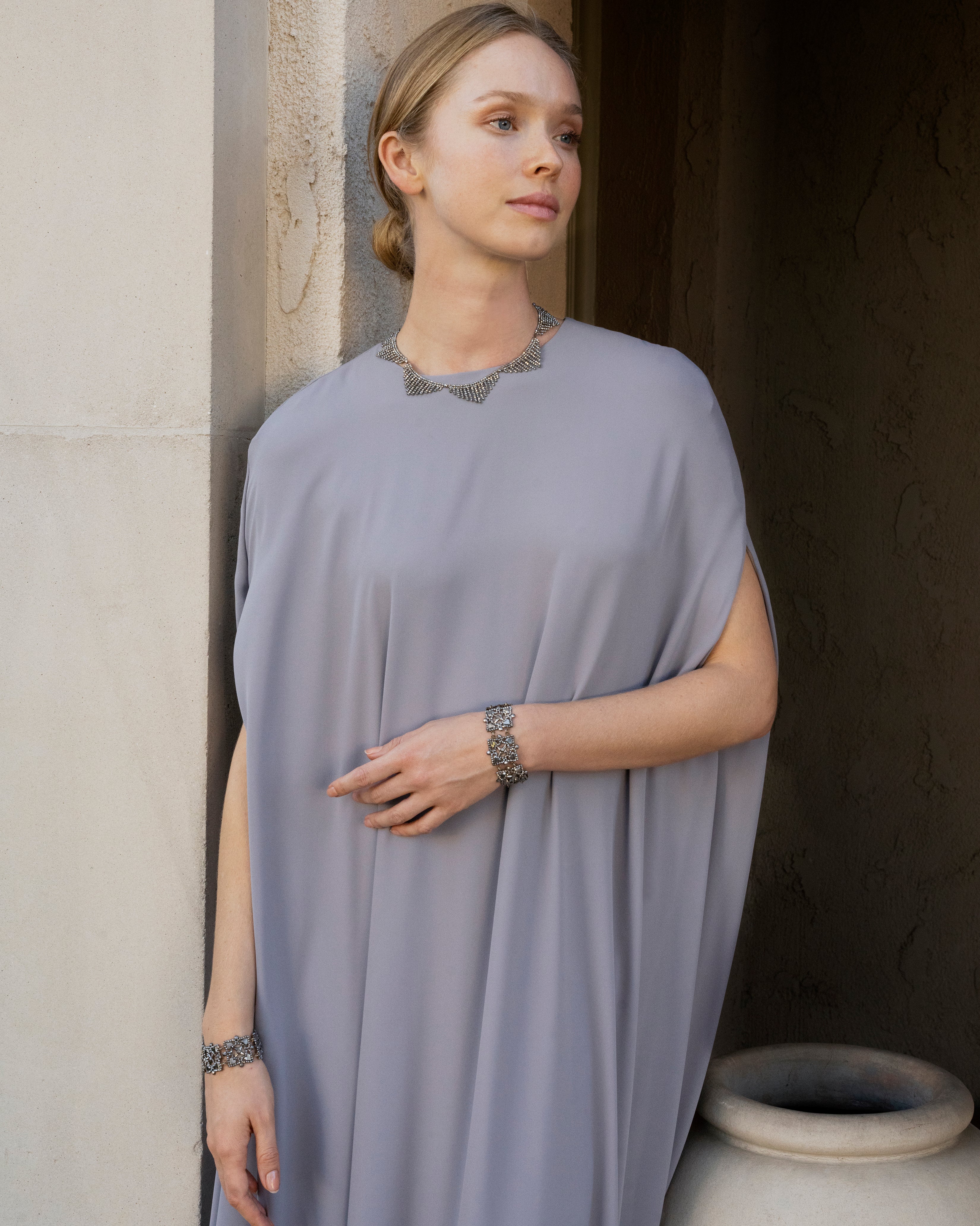 A model wearing a grey gown and a cut steel necklace with cut steel bracelets.