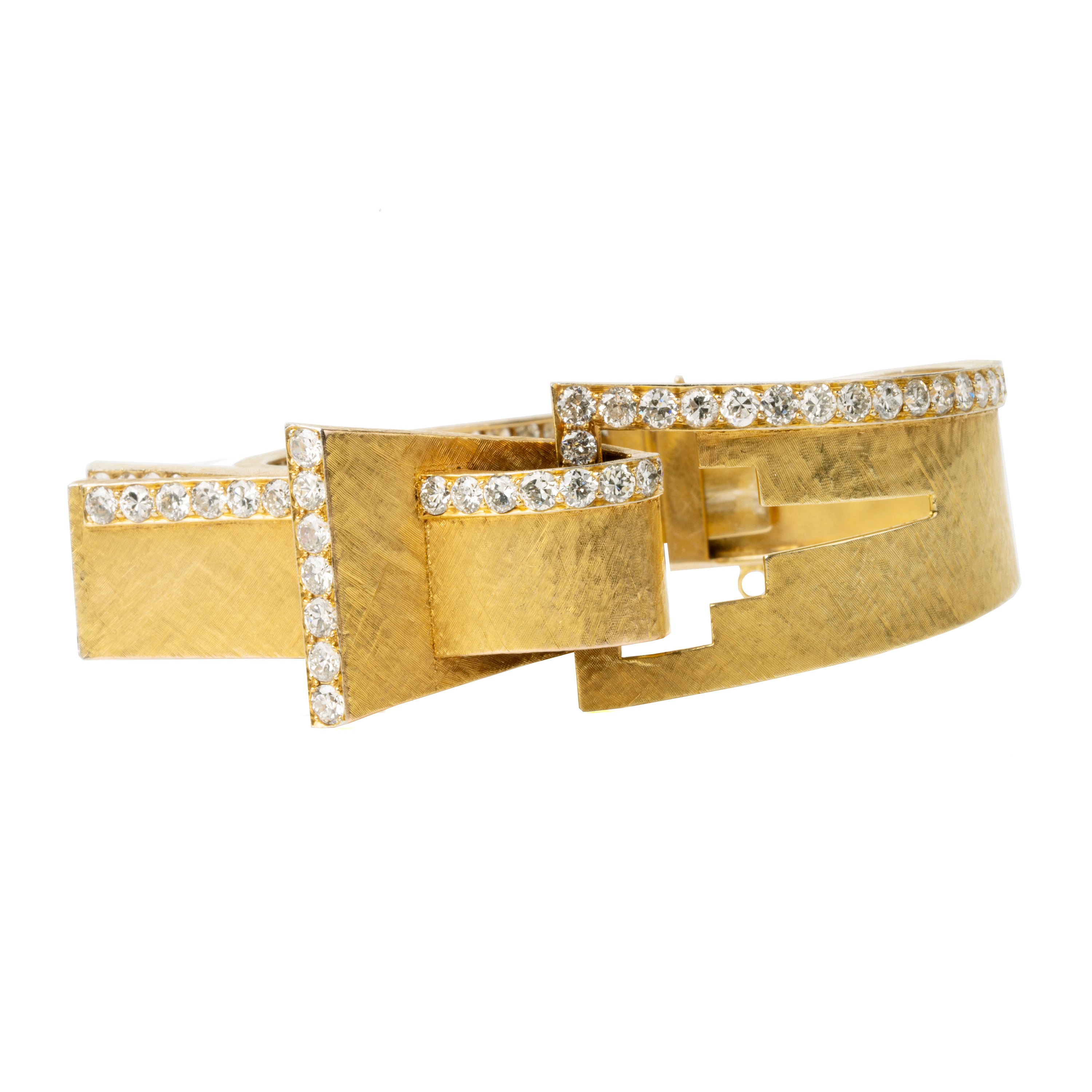 The American jewelry firm Trabert & Hoeffer, with the Parisian house Mauboussin, produced some of the most extraordinary jewels of its time. Famous for their illustrious Hollywood clientele. This chic 18k gold bangle has a florentine finish in an abstract buckle design with bright diamonds set in platinum.  American in origin.  Circa 1960.