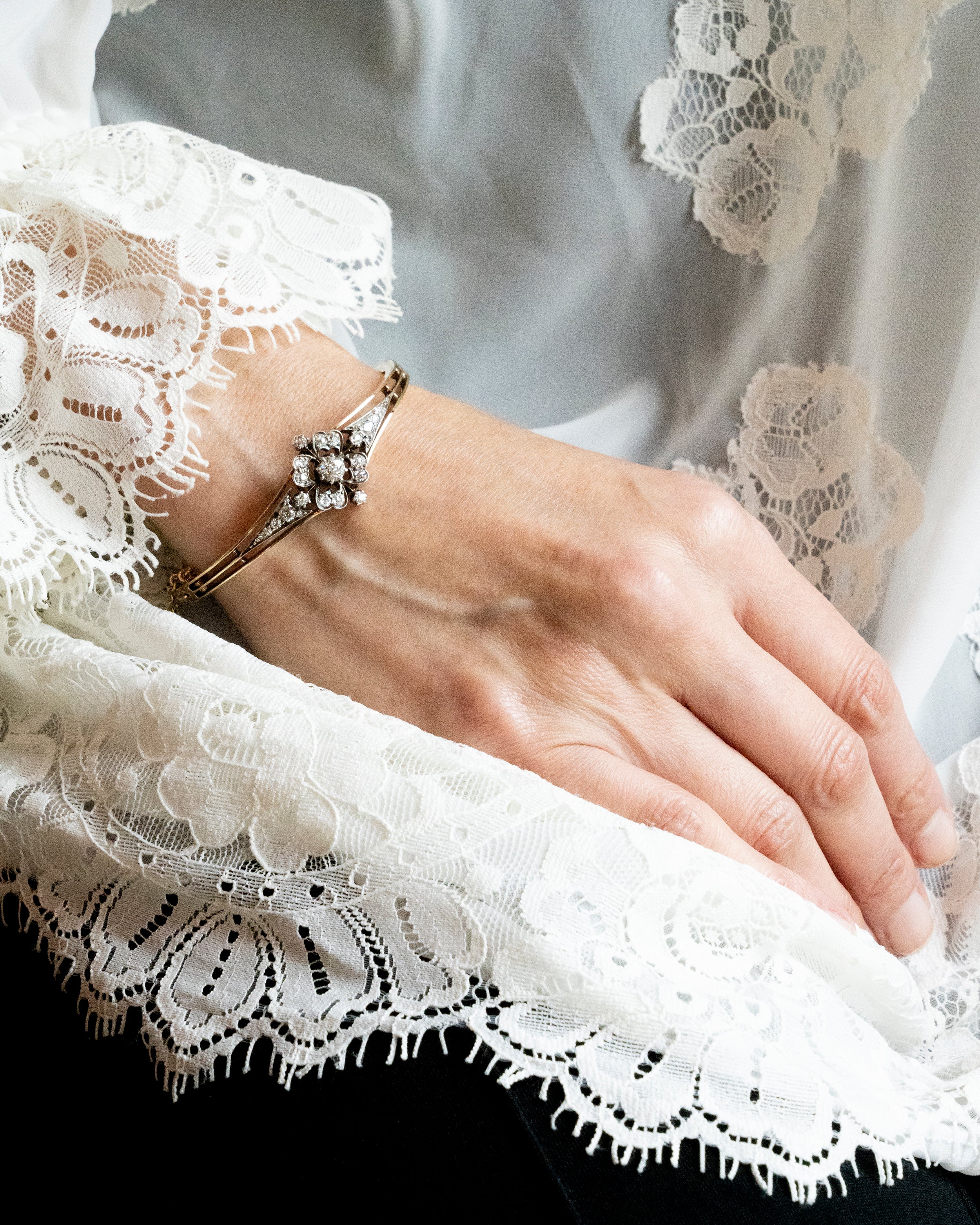 Late 19th century floral diamond bangle bracelet, in silver topped gold. The center diamond is an old mine cut diamond, approximately .75 carats, flanked by additional old mine cut diamonds. English in origin. Circa 1890. Bracelet on a model.