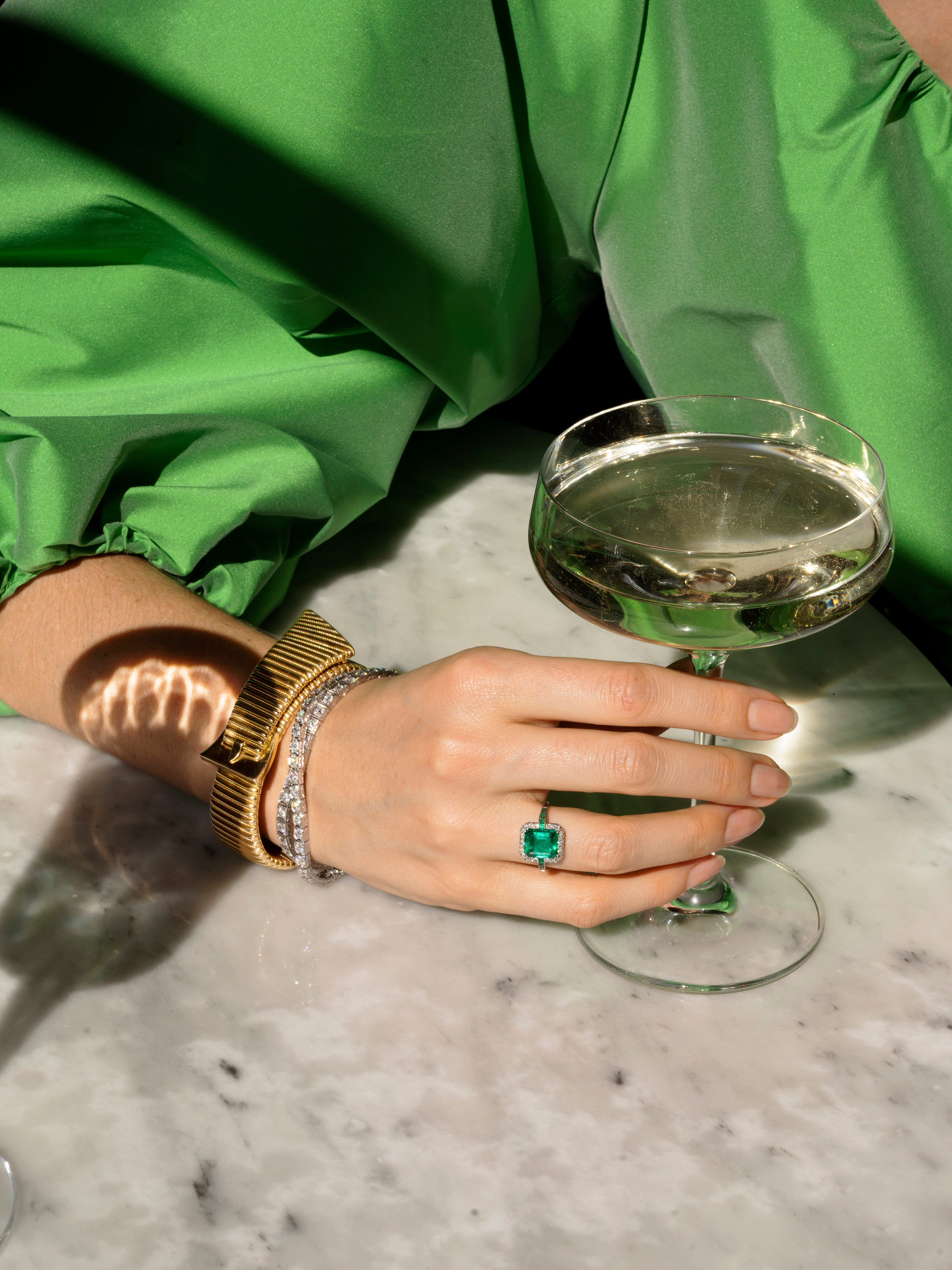Chic gas-pipe bracelet. An outstanding design with a clever locking clasp mechanism and a French maker's mark. French in origin. Mid 20th century. 18k gold. Model hold a glass of wine wearing the bracelet and an emerald and diamond ring.