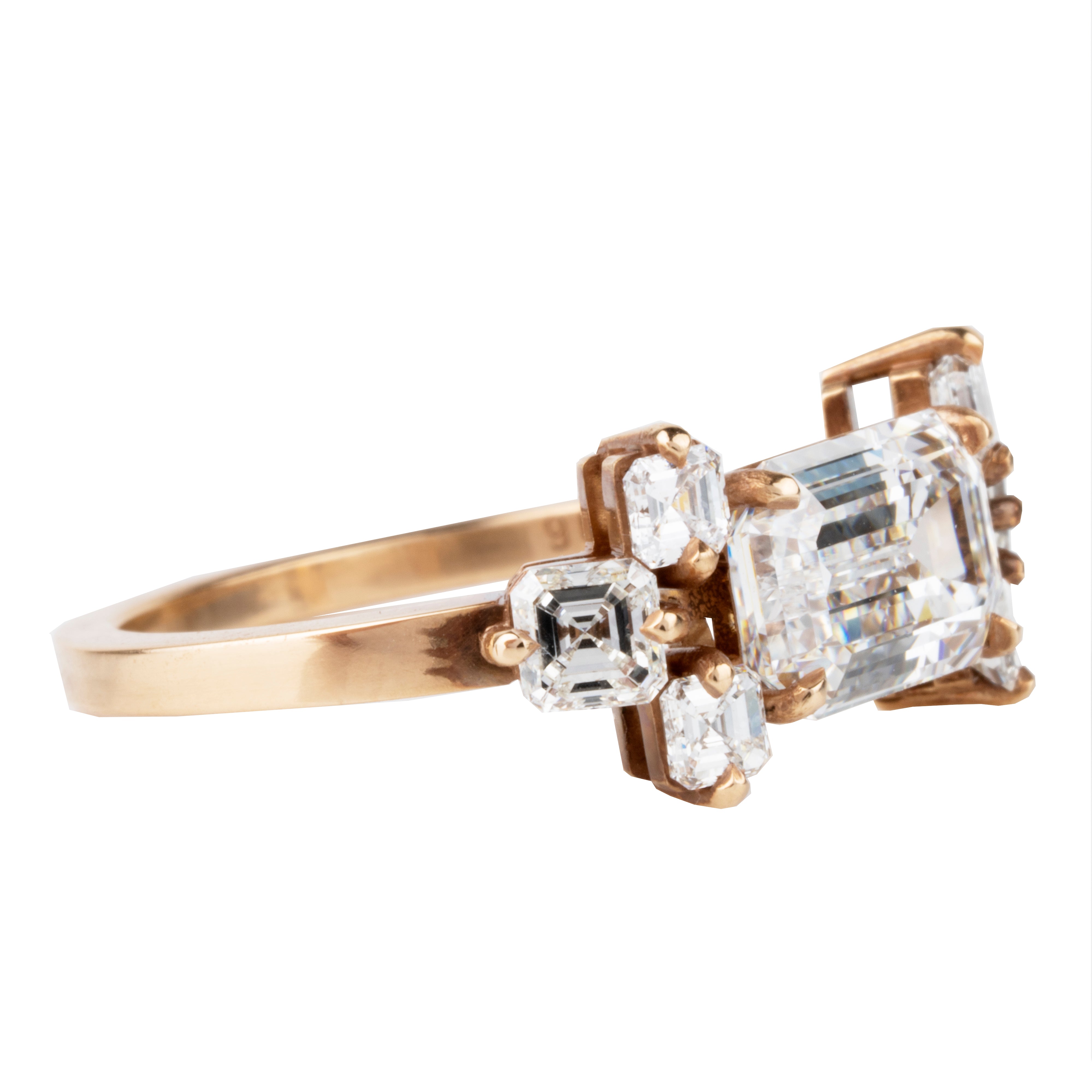 This seven stone ring was inspired by a 17th century diamond ring that we once had. The arrangement is characteristic of rings that date from 1650-1700. We modernized the look with six Asscher cut diamonds surrounding an emerald cut diamond. This ring features a GIA certified 2.05 carat emerald cut diamond, E color and VVS1 clarity. There are six Asscher cut diamonds, approximately .79 carats in total diamond weight, F color, and VS1/VS2 clarity. It was handcrafted in our 18k old gold. Side view.