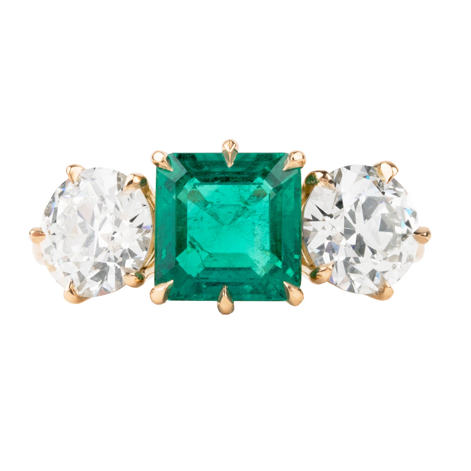 A three-stone emerald and diamond ring with a slim band, featuring a central emerald stone surrounded by two diamond side stones, all set in 18k old gold.
