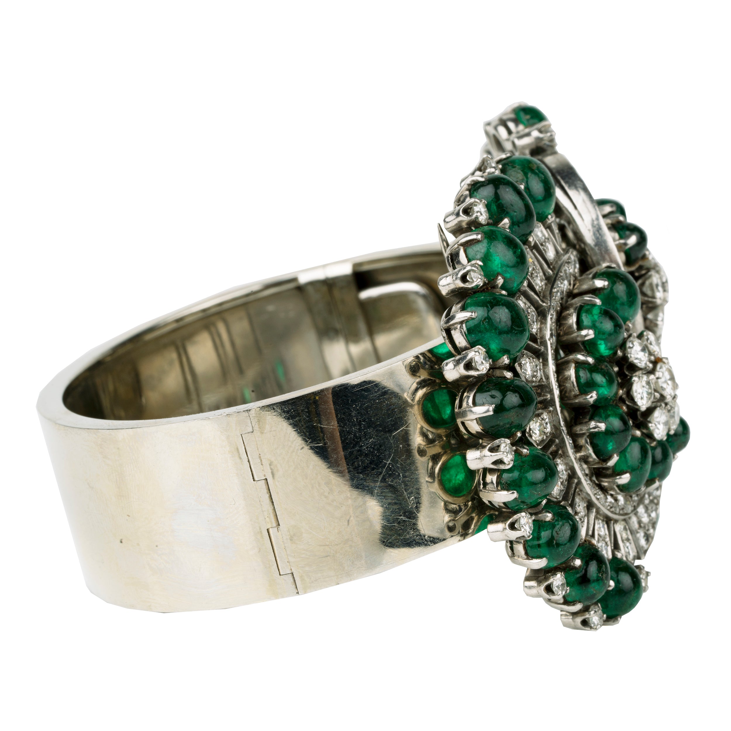 Retro emerald and diamond bracelet. This bold bangle bracelet is convertible into two separate dress clips allowing the bangle to be worn in reduced form. Bright emerald cabochon stones are set in a swirling pattern with diamonds. 18k white gold. Signed, Nieman Marcus. America, circa 1950.