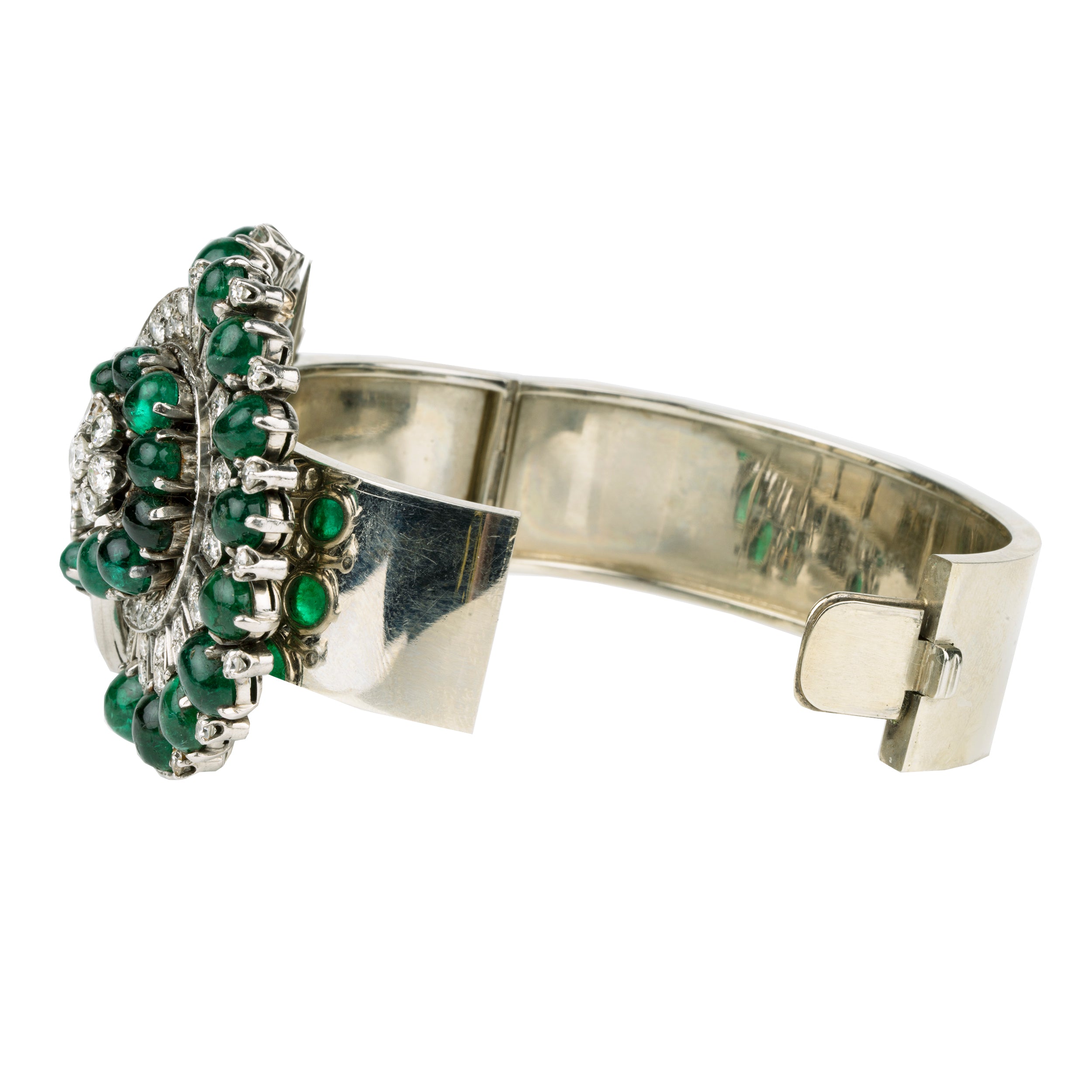 Retro emerald and diamond bracelet. This bold bangle bracelet is convertible into two separate dress clips allowing the bangle to be worn in reduced form. Bright emerald cabochon stones are set in a swirling pattern with diamonds. 18k white gold. Signed, Nieman Marcus. America, circa 1950.