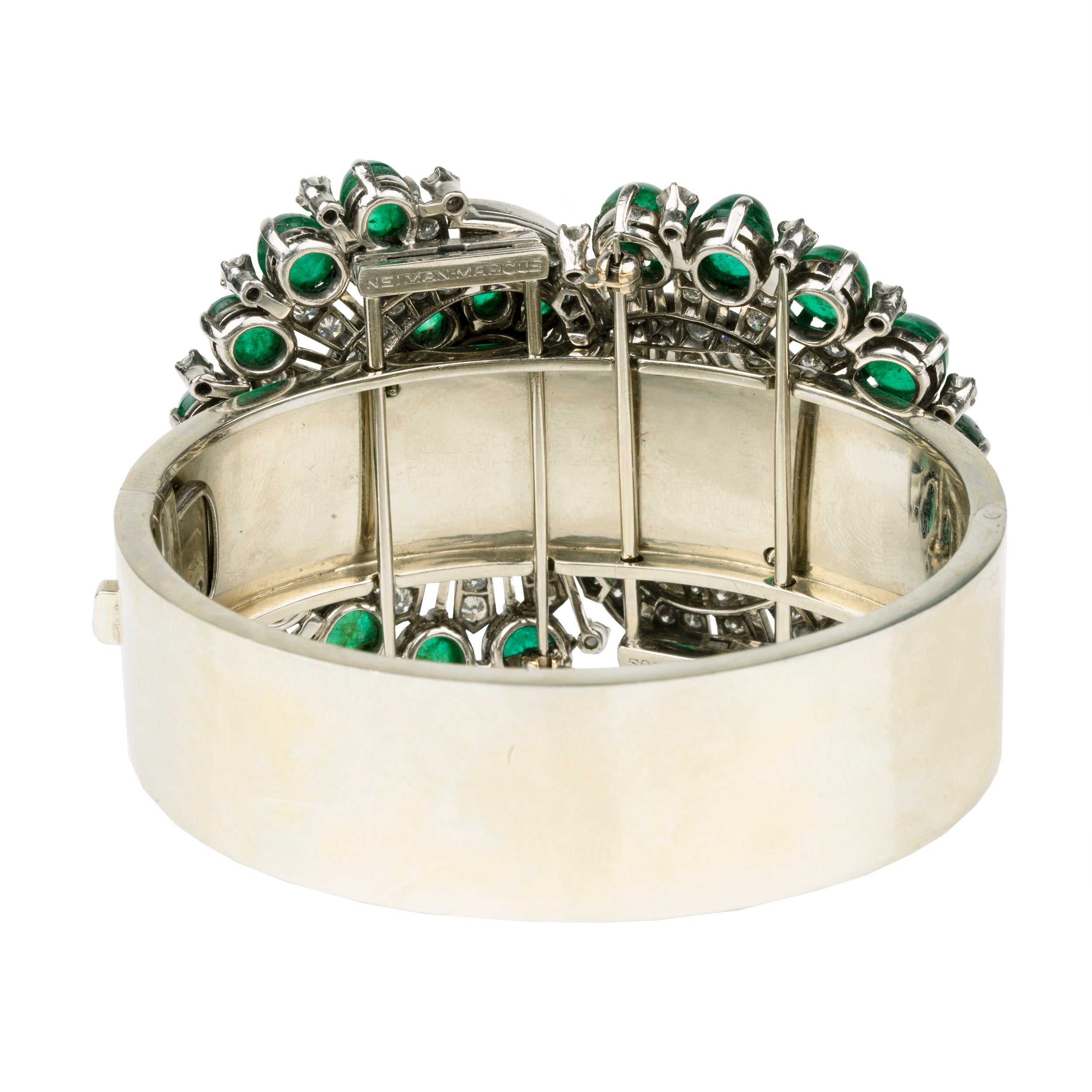 Retro emerald and diamond bracelet. This bold bangle bracelet is convertible into two separate dress clips allowing the bangle to be worn in reduced form. Bright emerald cabochon stones are set in a swirling pattern with diamonds. 18k white gold. Signed, Nieman Marcus. America, circa 1950.