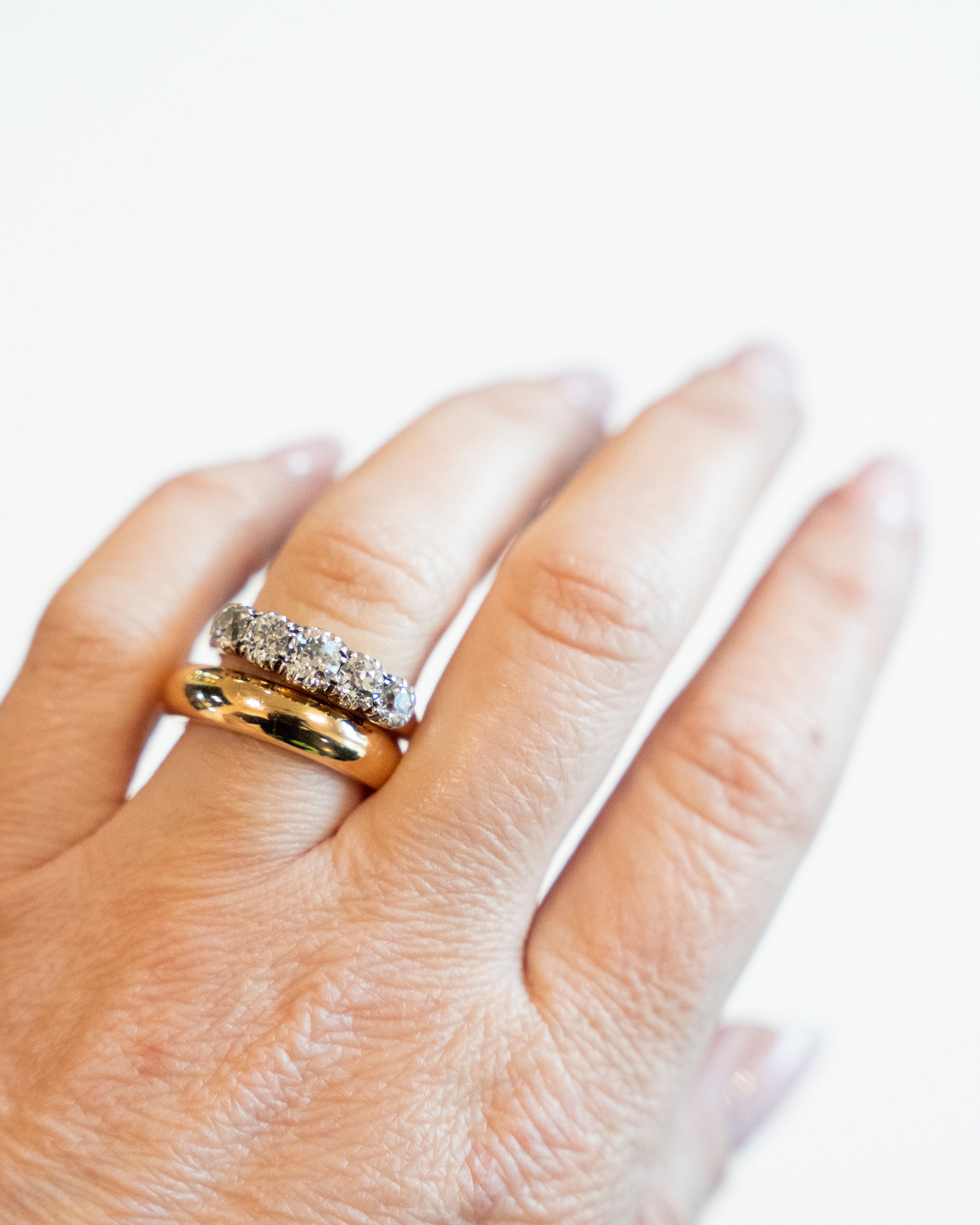 Victorian-era five-stone diamond ring, in a silver-topped gold setting. Five bright old mine-cut diamonds set in cutaway settings. England, circa 1860. Ring being modeled on the hand.