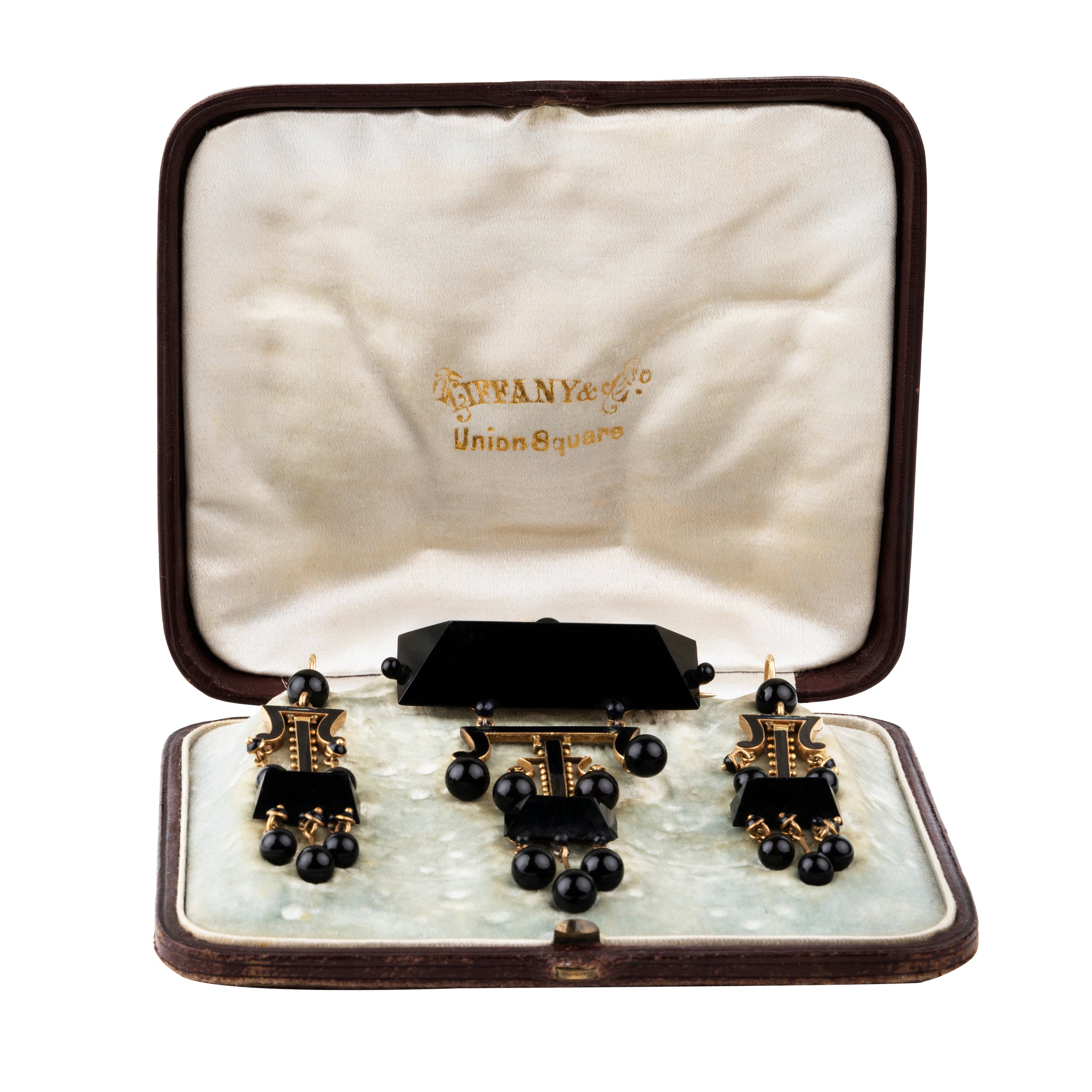 19th Century Tiffany & Company onyx earrings and brooch, in 18k gold. Carved onyx and black enamel details with the original box. American. Circa 1870.