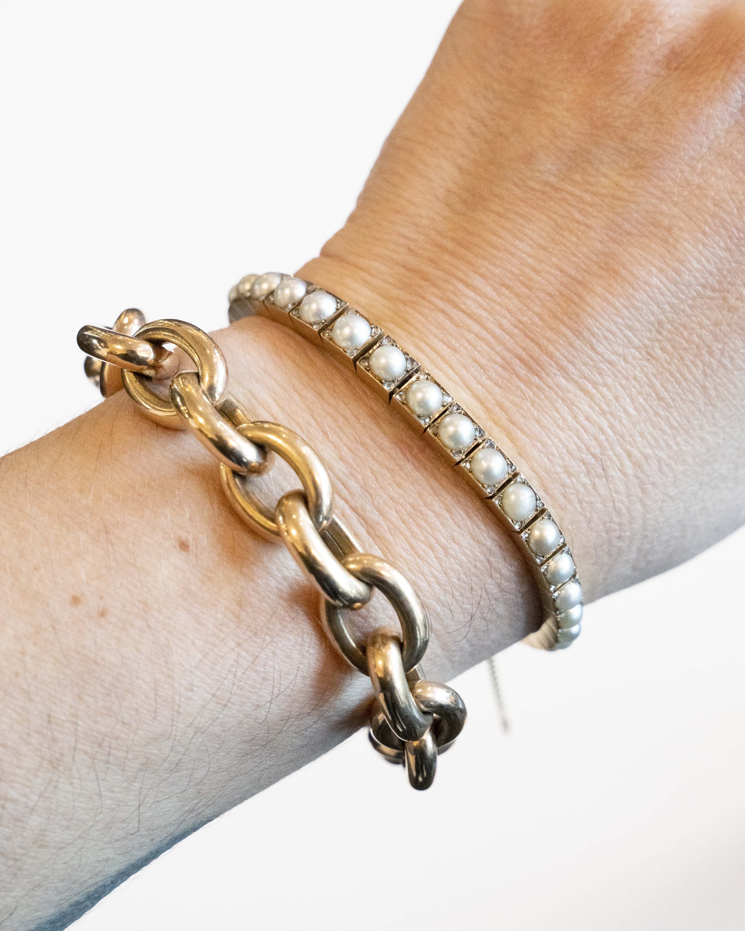 Edwardian era pearl and diamond line bracelet. White split pearls are set in 18k yellow gold. Each pearl is pointed with four rose cut diamonds in square settings. England, circa 1910.