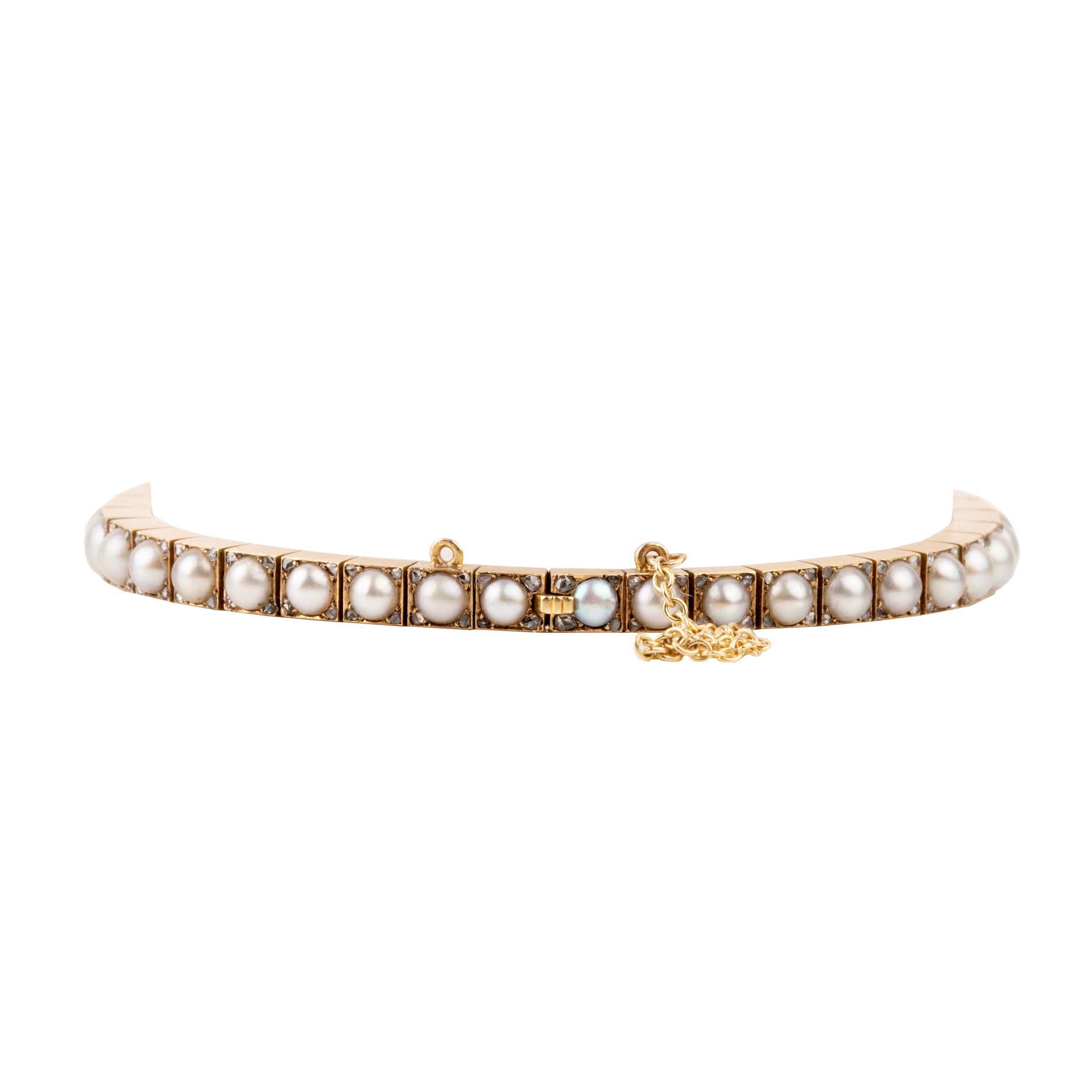 Edwardian era pearl and diamond line bracelet. White split pearls are set in 18k yellow gold. Each pearl is pointed with four rose cut diamonds in square settings. England, circa 1910. Side view.