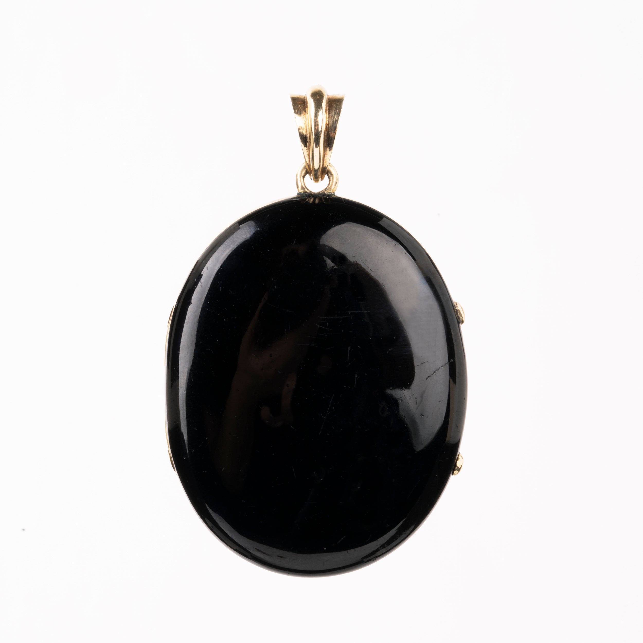 A bold black enamel locket with a pearl starburst motif. The locket is crafted in 18k gold. It opens to reveal two compartments for photographs or keepsakes. England, circa 1870.