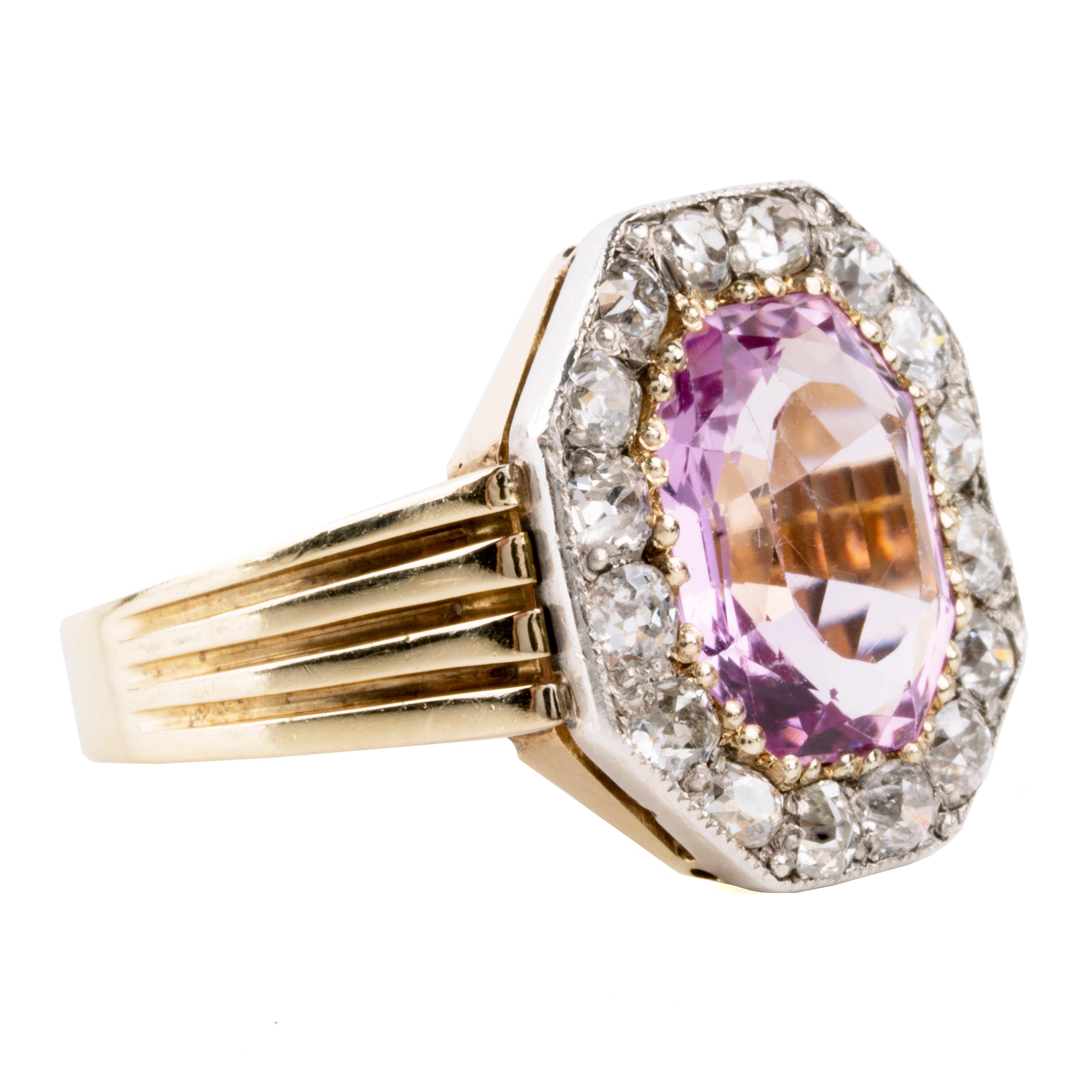 Striking ring with a large, vibrant pink precious topaz stone. It has very crisp clarity and rich color. The photographs do not capture the depth of color. There are sixteen mixed-cut antique diamonds surrounding the primary stone. Old Mine and old European cuts are set in platinum, while the rest of the ring is in 18k gold. England, circa 1900. Side view.