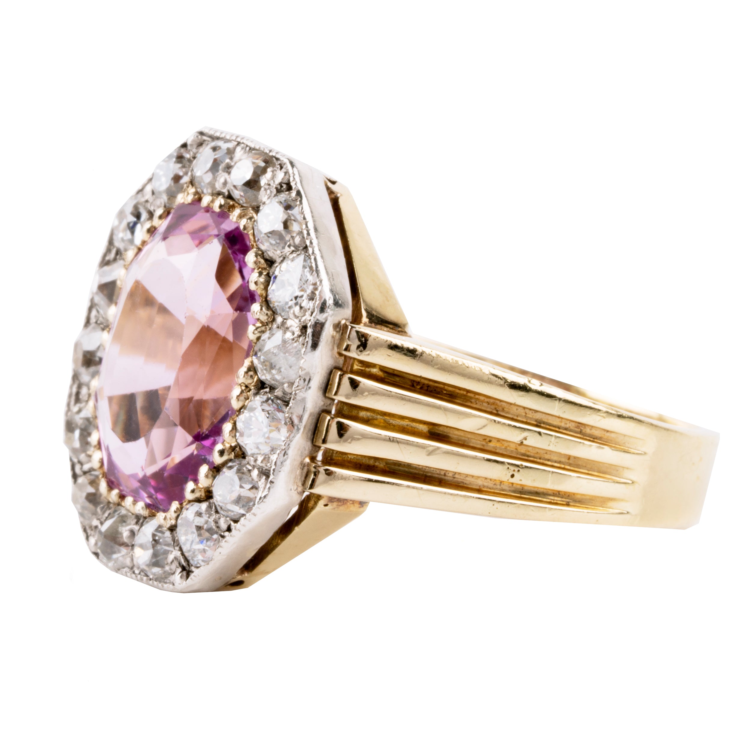 Striking ring with a large, vibrant pink precious topaz stone. It has very crisp clarity and rich color. The photographs do not capture the depth of color. There are sixteen mixed-cut antique diamonds surrounding the primary stone. Old Mine and old European cuts are set in platinum, while the rest of the ring is in 18k gold. England, circa 1900. Side view.