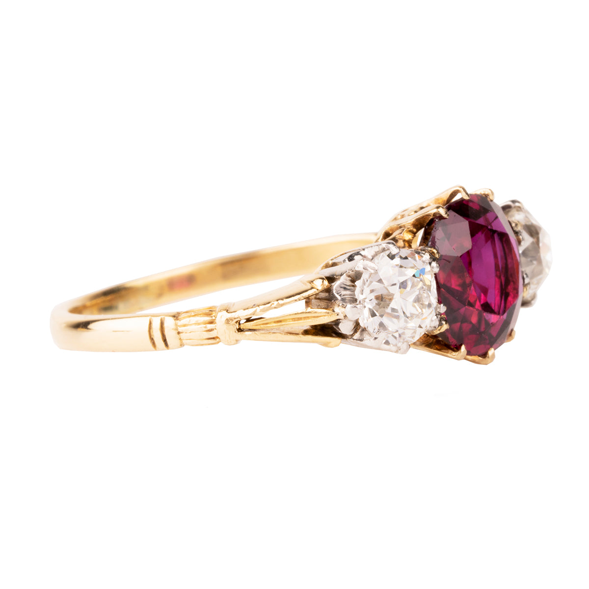 A classic ruby and diamond ring three stone ring. The ring features a natural red 2.11 carat ruby certified to have no treatment and be of Thai origin. The primary stone is flanked by two old European cut diamonds weighing approximately .5 carat each. The ring is set in 18k yellow gold and platinum.  English in Origin. Circa 1910. The stone holds a certificate from GCS laboratory in London. Certificate number:5784-2538. Side view.