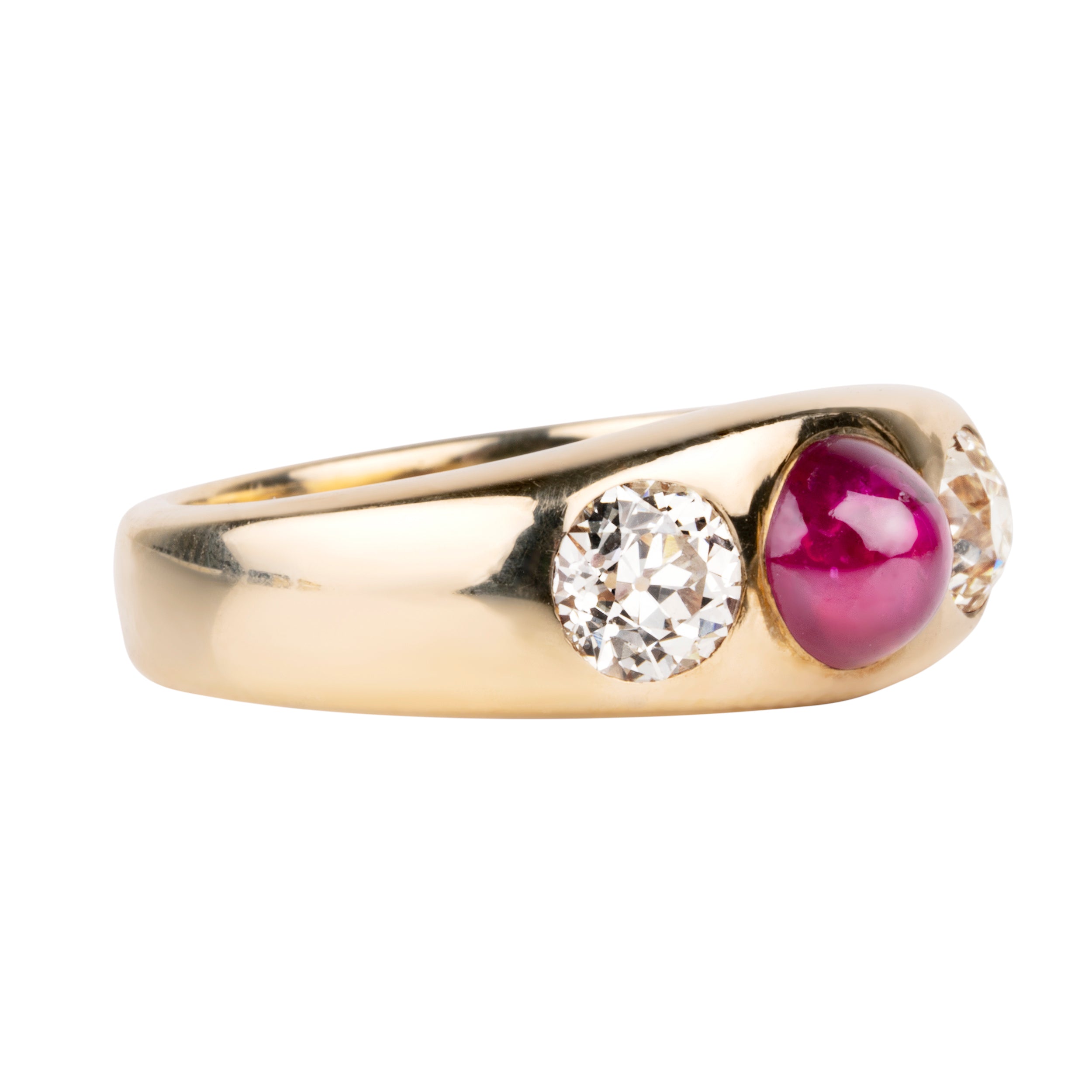 Early 20th century ruby and diamond three stone ring. In a flush 18k gold setting. Two old European cut diamonds flank a bright Burmese ruby cabochon with a high dome. English in origin. Circa 1910. Side view.