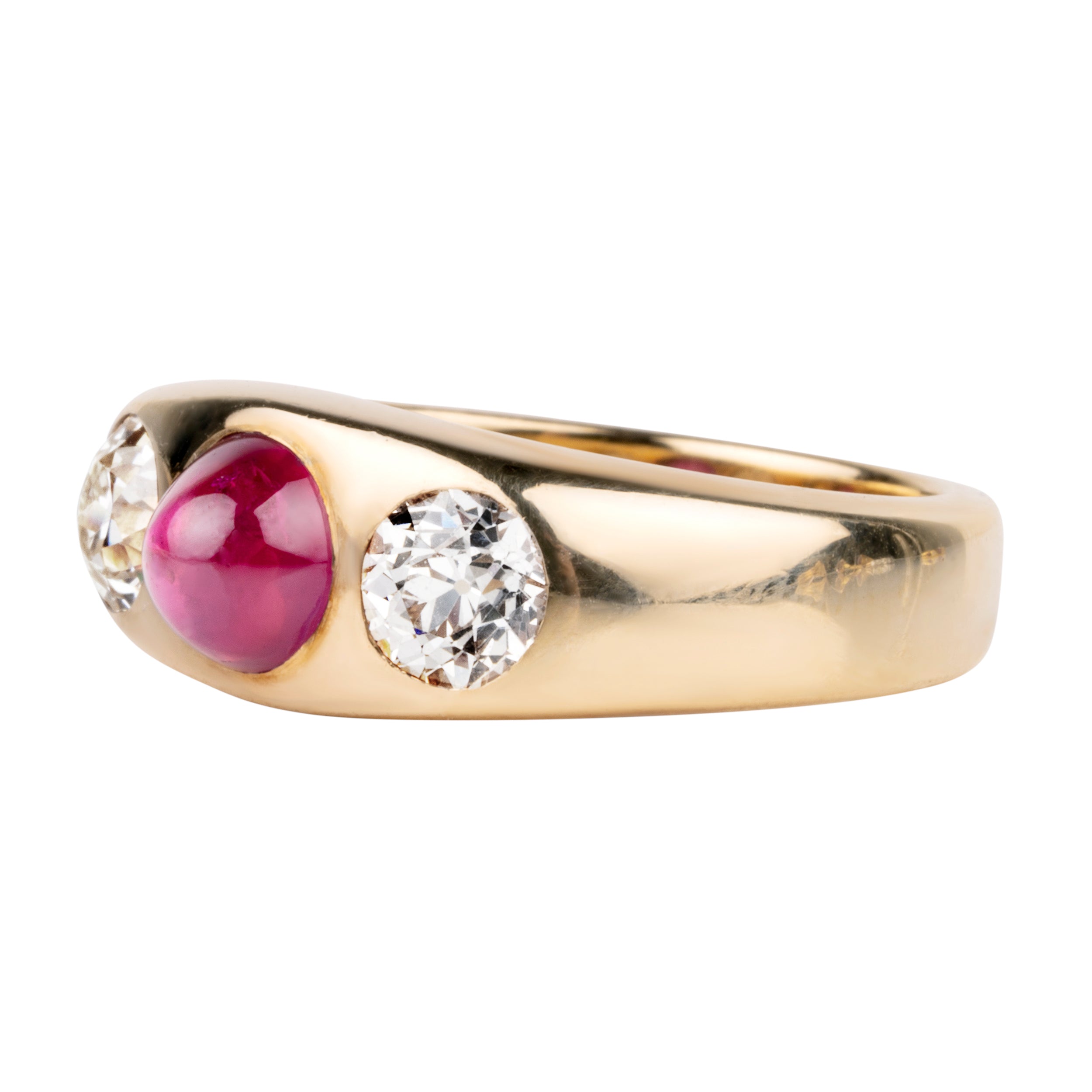 Early 20th century ruby and diamond three stone ring. In a flush 18k gold setting. Two old European cut diamonds flank a bright Burmese ruby cabochon with a high dome. English in origin. Circa 1910. Side view.