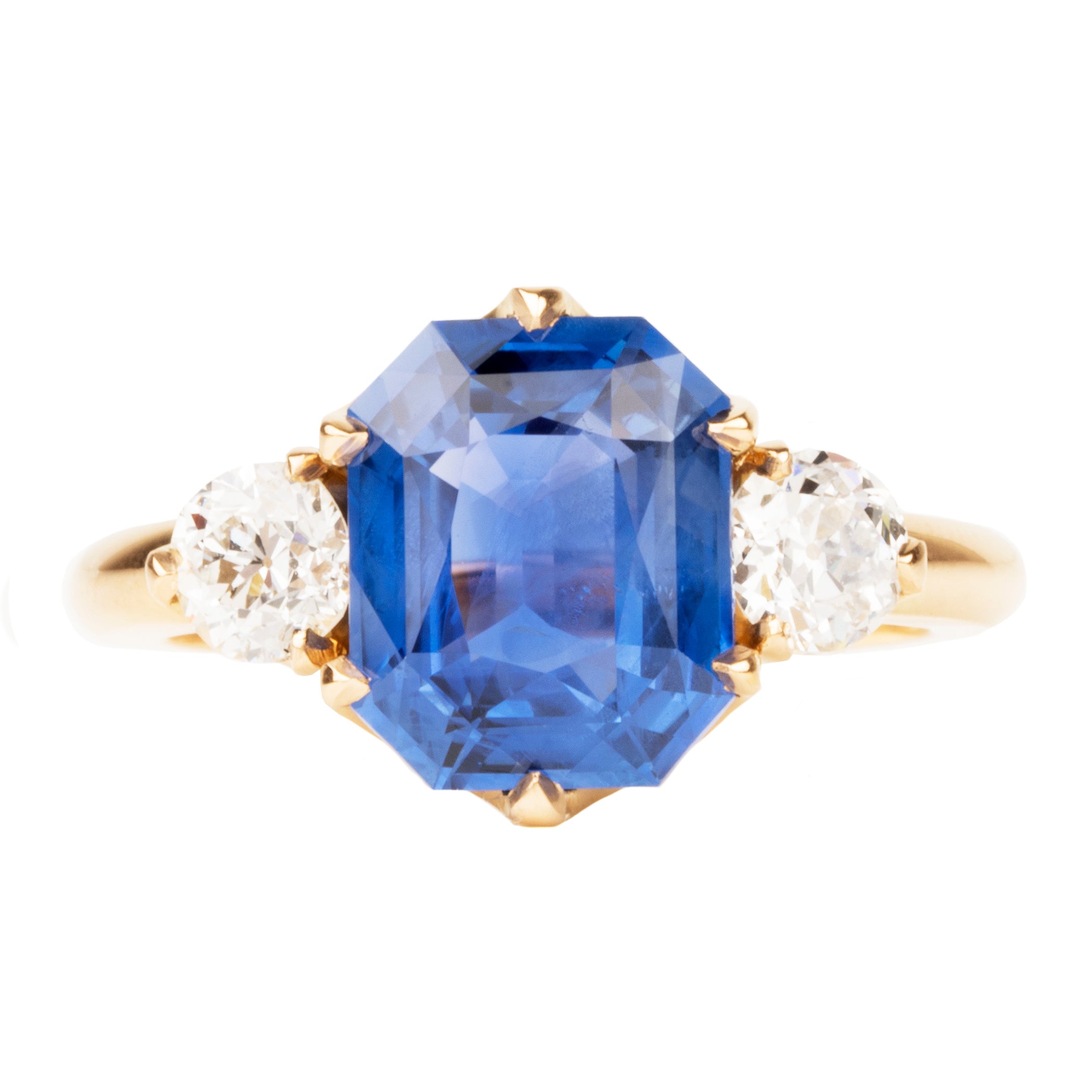 A three-stone ring with a large blue sapphire centerpiece and two smaller old European cut diamonds, all set in a gold band.