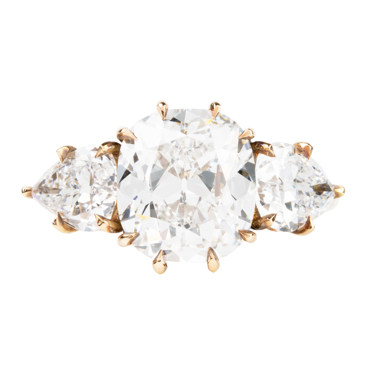 A ring with a cushion cut and two pear cut diamonds set in a gold band.