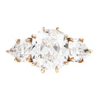 A ring with a cushion cut and two pear cut diamonds set in a gold band.