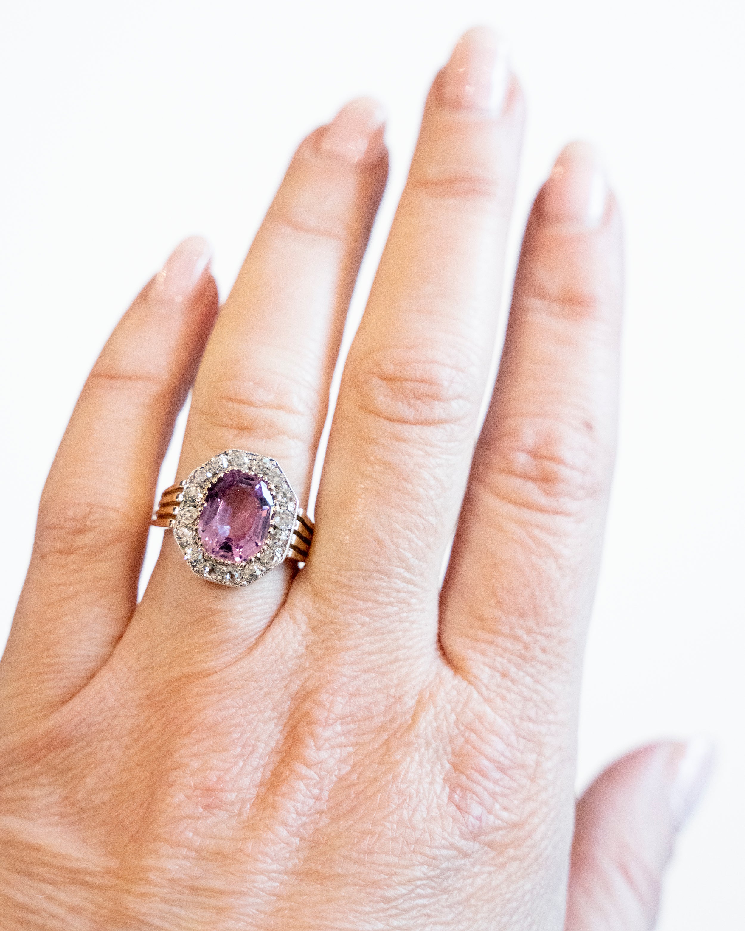 Striking ring with a large, vibrant pink precious topaz stone. It has very crisp clarity and rich color. The photographs do not capture the depth of color. There are sixteen mixed-cut antique diamonds surrounding the primary stone. Old Mine and old European cuts are set in platinum, while the rest of the ring is in 18k gold. England, circa 1900. Being modeled on a hand.