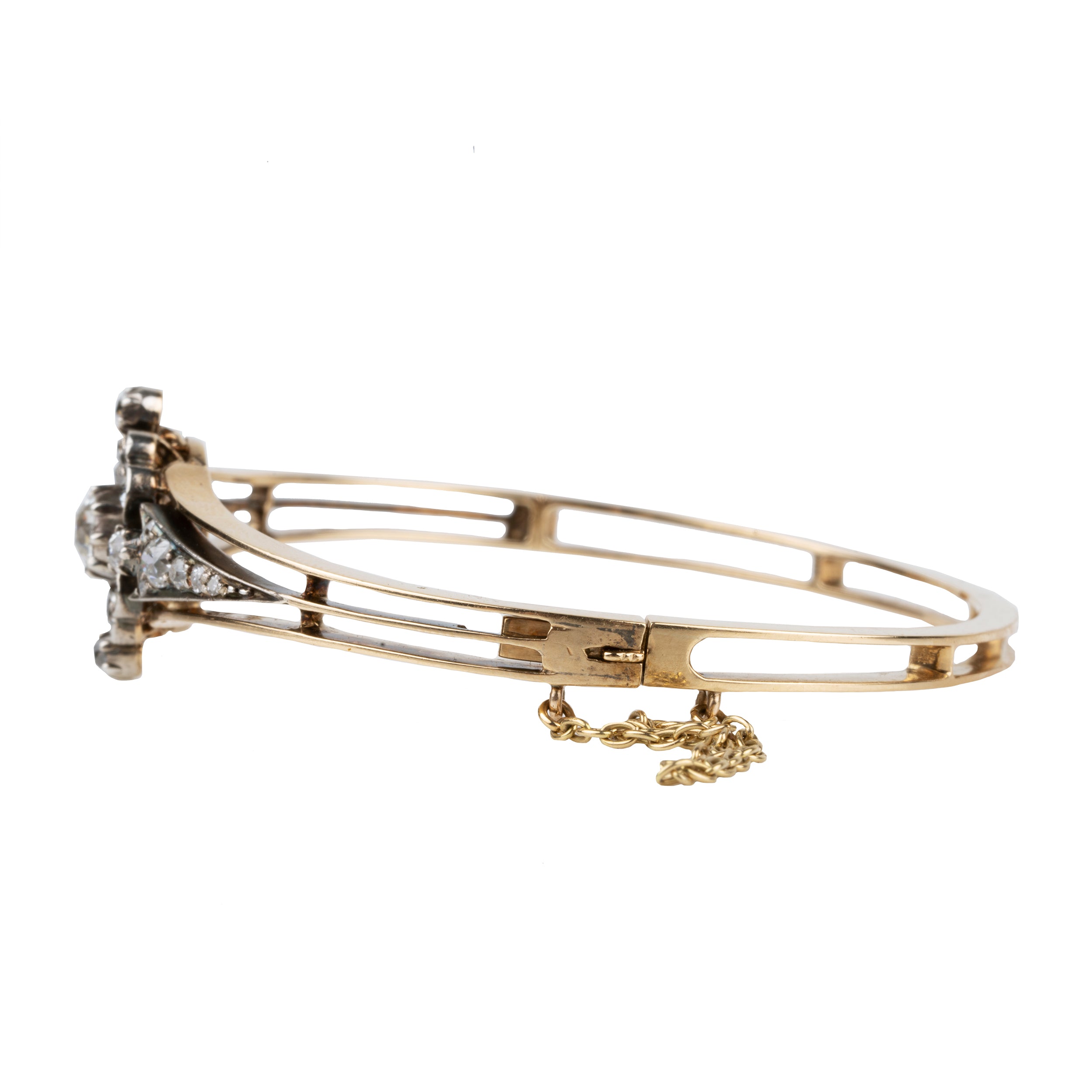 Late 19th century floral diamond bangle bracelet, in silver topped gold. The center diamond is an old mine cut diamond, approximately .75 carats, flanked by additional old mine cut diamonds. English in origin. Circa 1890. Side view with the safety chain.