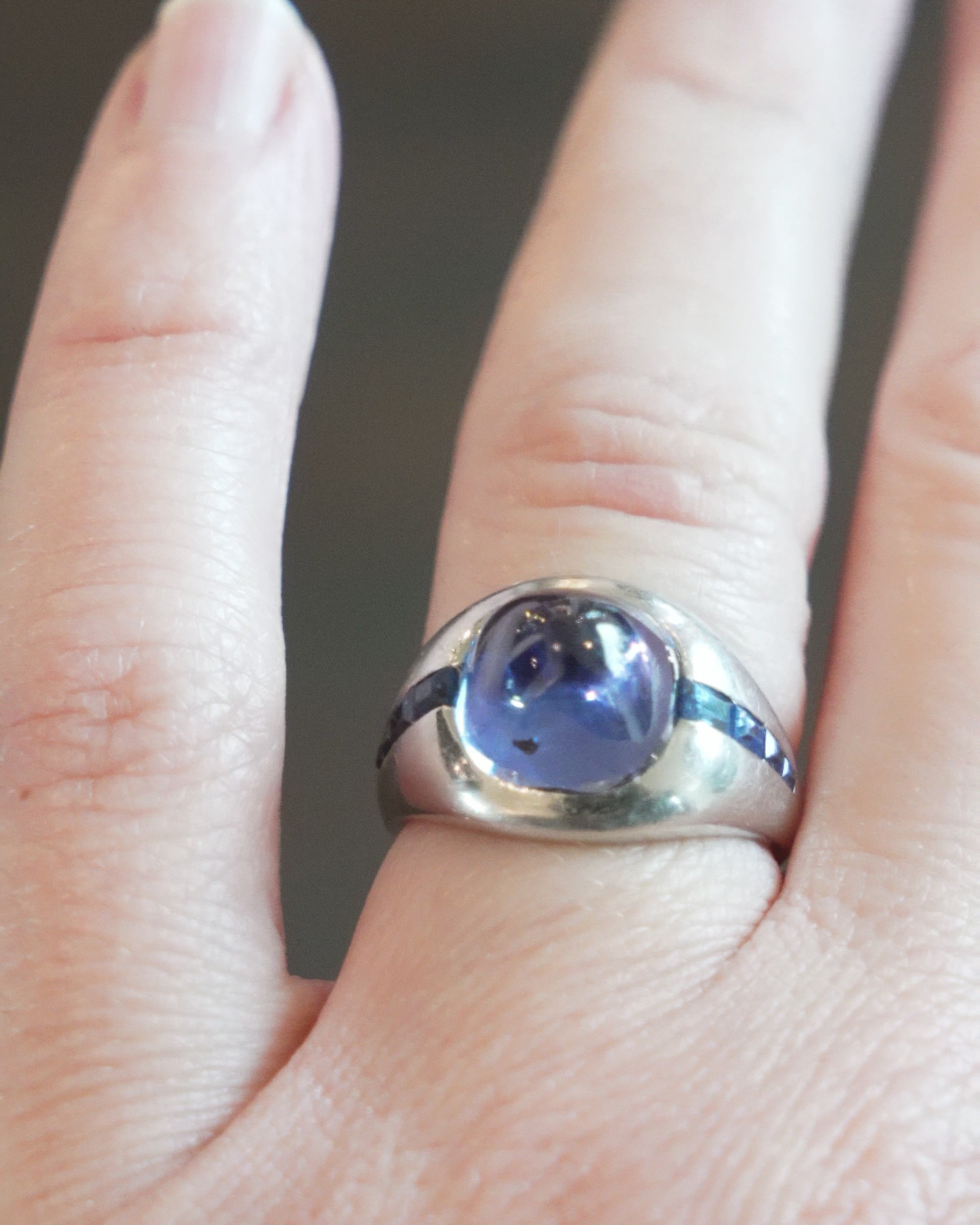 Early 20th-century platinum ring with unique high-domed Sugarloaf cabochon sapphire in a heavy platinum setting. Approximately 5 carat no-heat Ceylon Sapphire with AGL certificate indicating origin and no treatment of any kind. Beautiful cornflower blue with matched step-cut side stones. The center stone has fantastic clarity.Circa 1920.