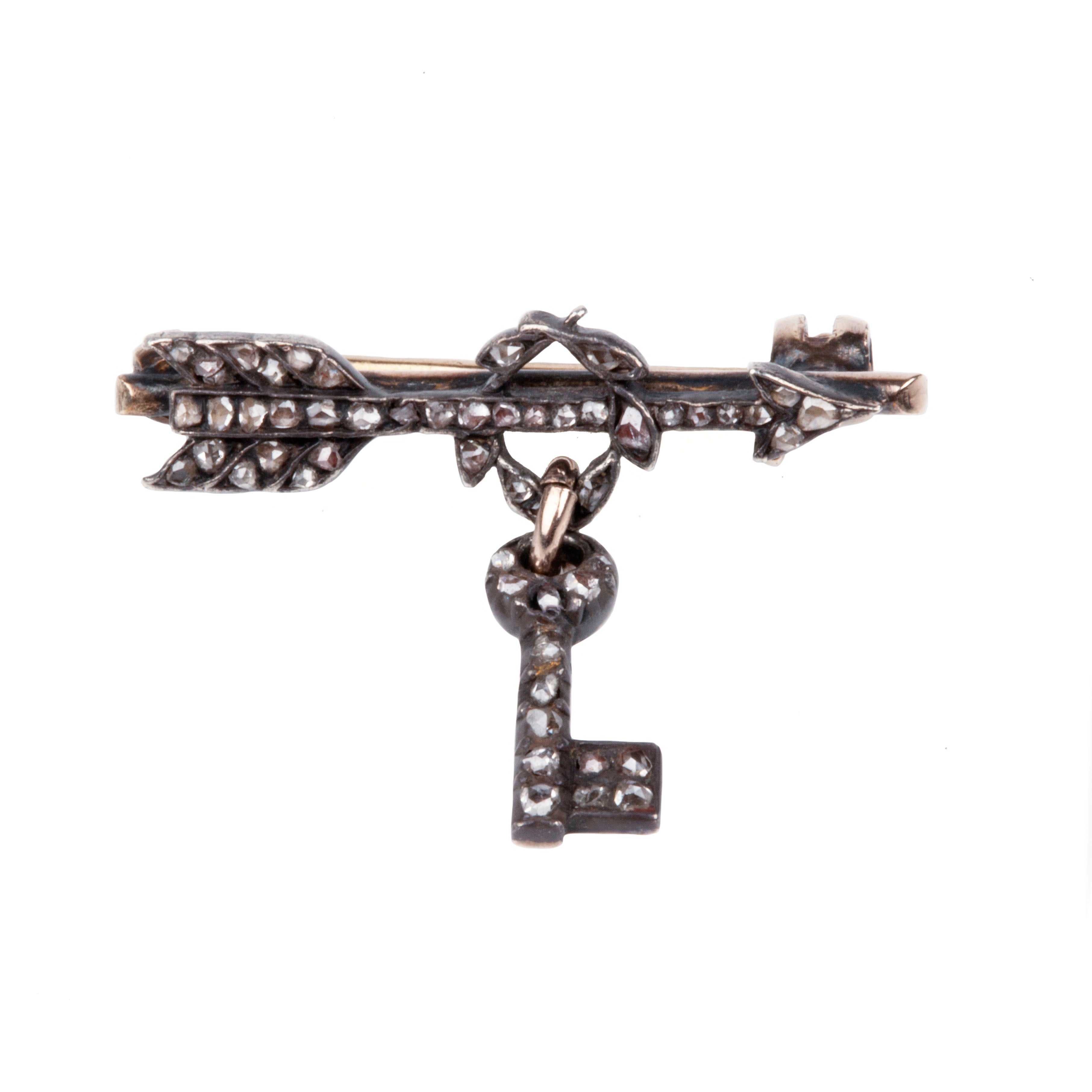 Tiny Victorian era Rose cut diamond arrow brooch with the tiniest key hanging from a laurel wreath. Silver topped gold with original clasp fixture. English in Origin. Circa 1860. Close-up view.