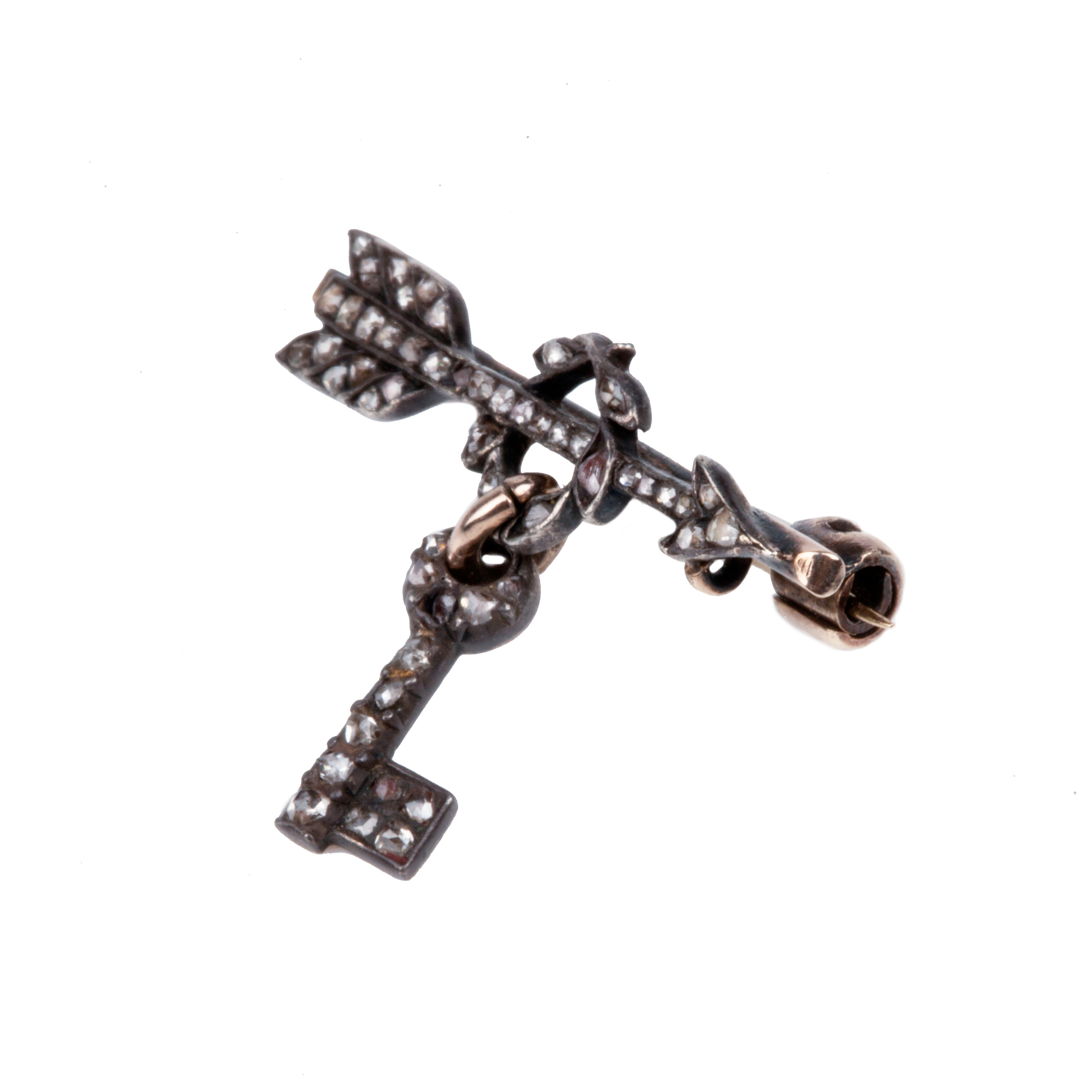 Tiny Victorian era Rose cut diamond arrow brooch with the tiniest key hanging from a laurel wreath. Silver topped gold with original clasp fixture. English in Origin. Circa 1860. Close-up view.