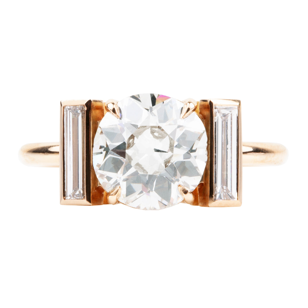 An elegant ring featuring a central old European cut diamond with bezel set vertical baguettes, in a simple four-prong setting, handcrafted in 18k old gold.