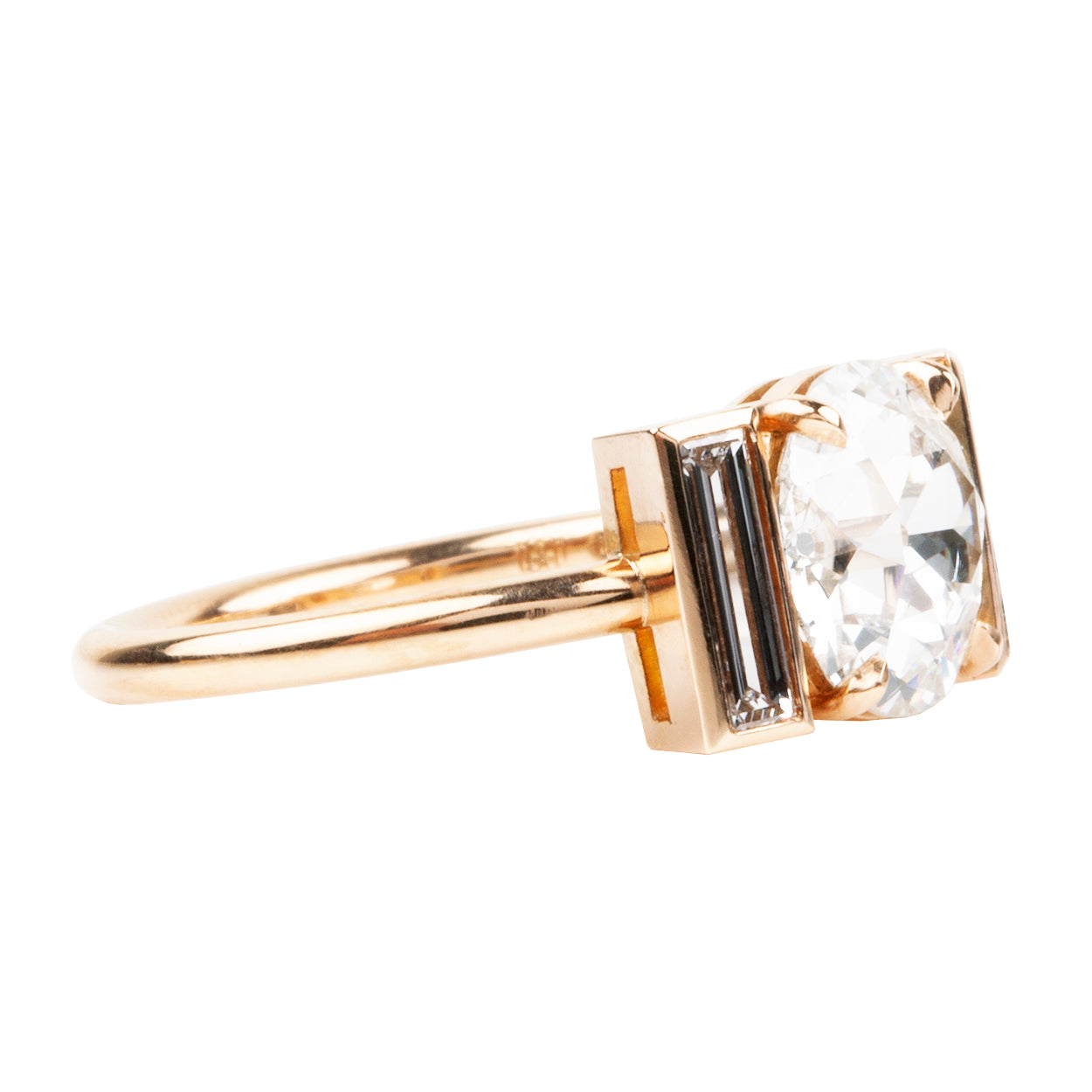 An elegant ring featuring a central old European cut diamond with bezel set vertical baguettes, in a simple four-prong setting, handcrafted in 18k old gold.