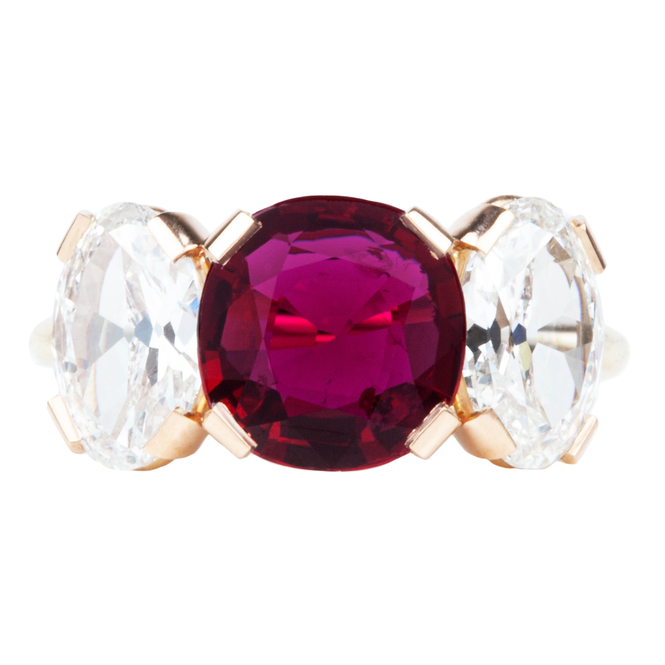 A ring featuring a red cushion-shaped ruby centerpiece flanked by two clear, old cut oval-shaped diamonds, all set in a simple, low profile band.