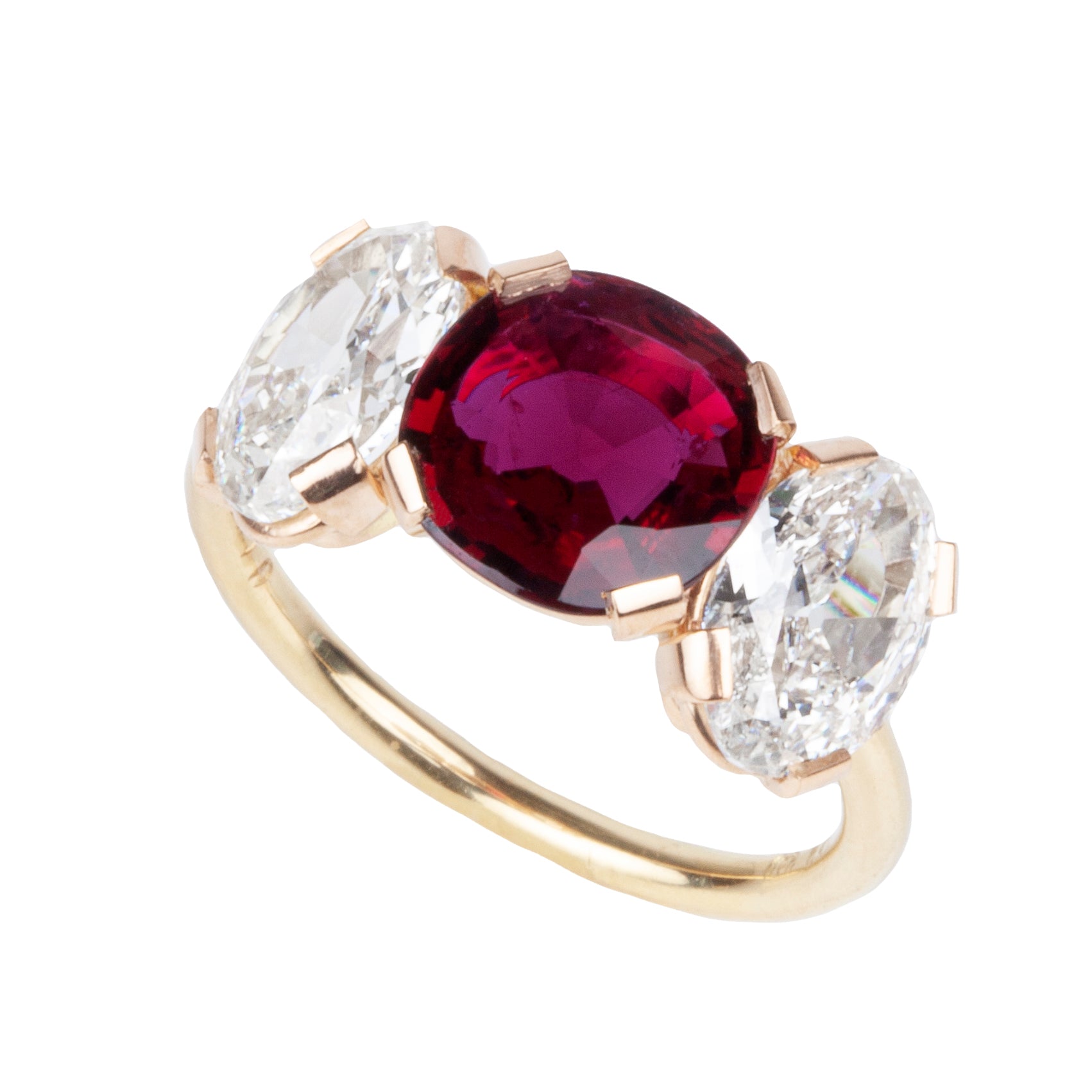 A ring featuring a red cushion-shaped ruby centerpiece flanked by two clear, old cut oval-shaped diamonds, all set in a simple, low profile band.