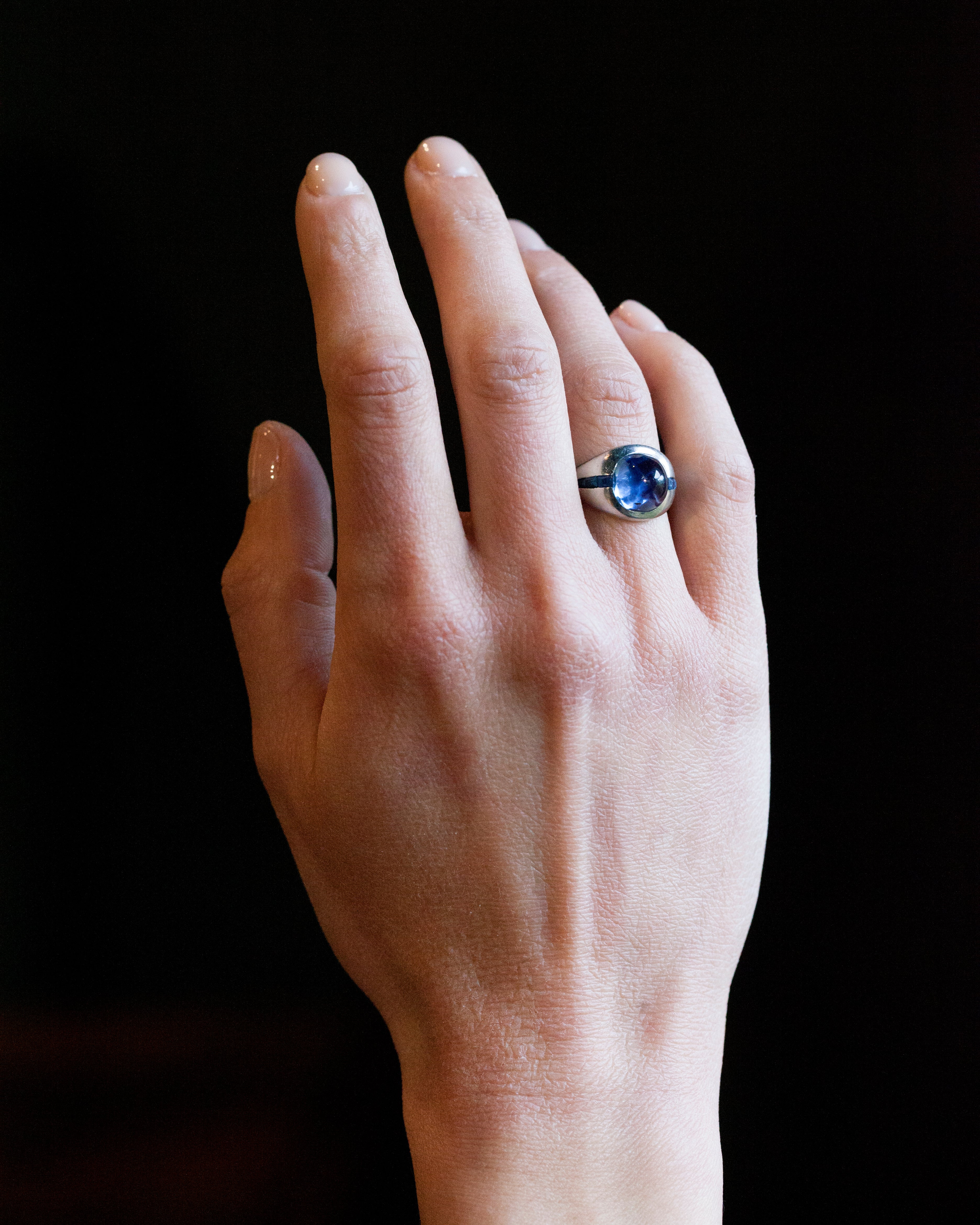 Early 20th-century platinum ring with unique high-domed Sugarloaf cabochon sapphire in a heavy platinum setting. Approximately 5 carat no-heat Ceylon Sapphire with AGL certificate indicating origin and no treatment of any kind. Beautiful cornflower blue with matched step-cut side stones. The center stone has fantastic clarity.Circa 1920.