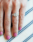 A classic three stone ring with a central cushion cut diamond and two round brilliant cut diamonds, handcrafted in 18k old gold with a simple band.