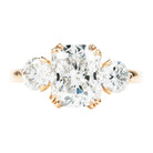 A classic three stone ring with a central cushion cut diamond and two round brilliant cut diamonds, handcrafted in 18k old gold with a simple band.