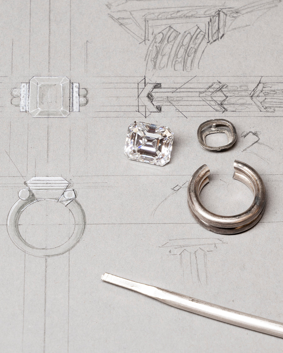 A drawing of the diamond ring in the works with the diamond laying next to it. 