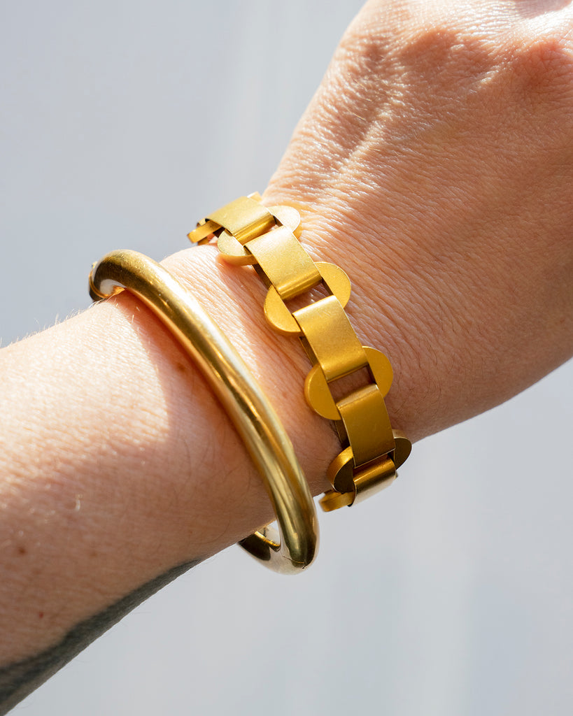 stacked gold bracelets being worn by a model for scale. 
