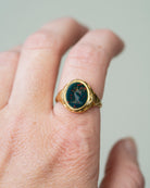 Victorian era deer intaglio signet ring, in 18k gold. Carved bloobstone intaglio depicted a deer holding a brand of leaves set in an engraved gold ring. England. Circa 1870. Modeled on a hand. 