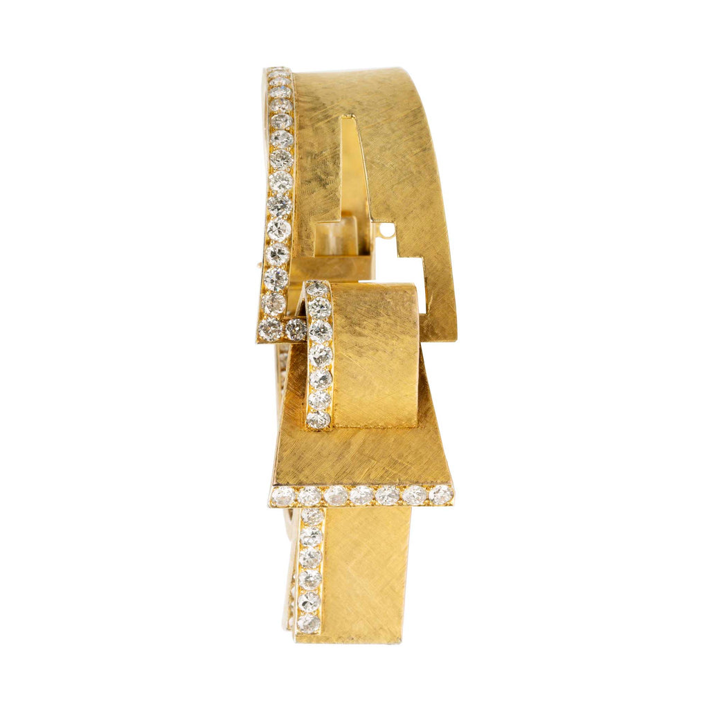 The American jewelry firm Trabert &amp; Hoeffer, with the Parisian house Mauboussin, produced some of the most extraordinary jewels of its time. Famous for their illustrious Hollywood clientele. This chic 18k gold bangle has a florentine finish in an abstract buckle design with bright diamonds set in platinum. In the design of the famed Chrysler Building in New York City. American in origin.Circa 1960.