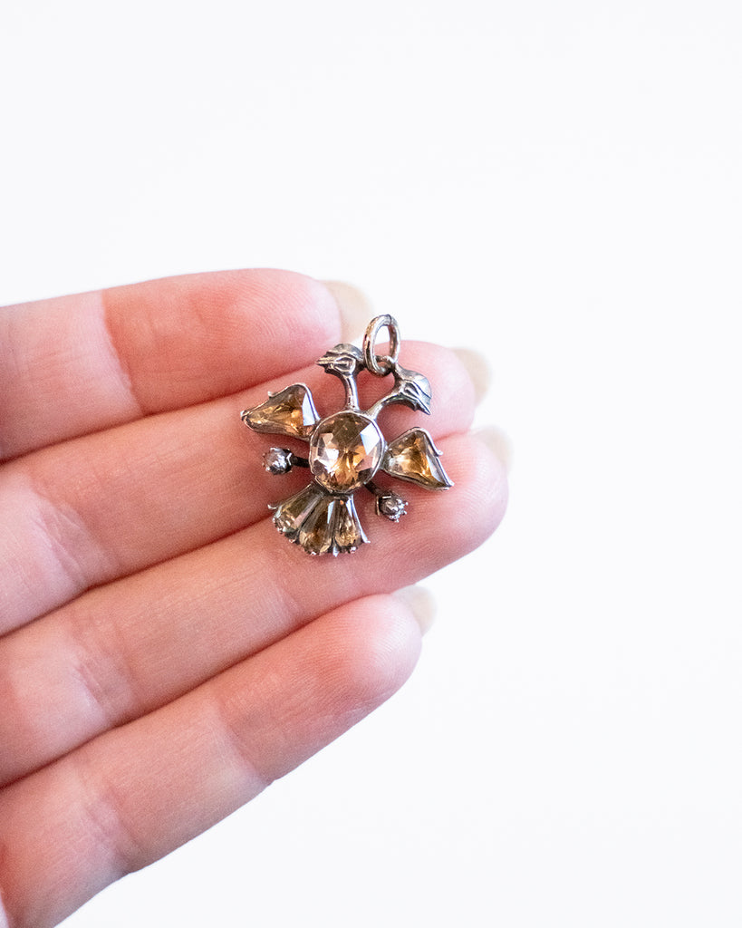 The Double-Headed Eagle is a symbol dating back to ancient cultures such as the Egyptians, Babylonians. This interpretation dates to the late 18th-century and would be Portuguese or Spanish in origin. Circa 1770. A hand holding the pendant for scale. 