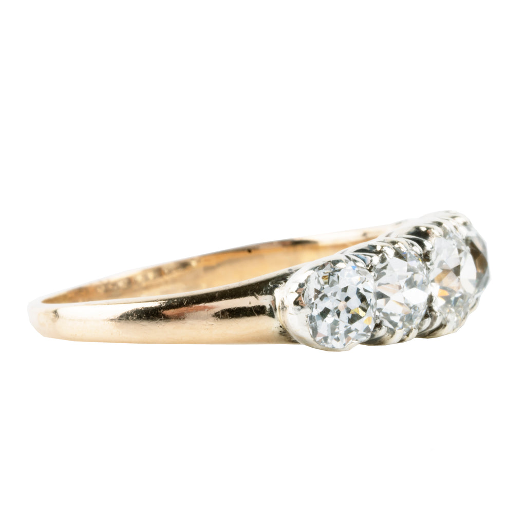 Victorian-era five-stone diamond ring, in a silver-topped gold setting. Five bright old mine-cut diamonds set in cutaway settings. England, circa 1860. Side view. 