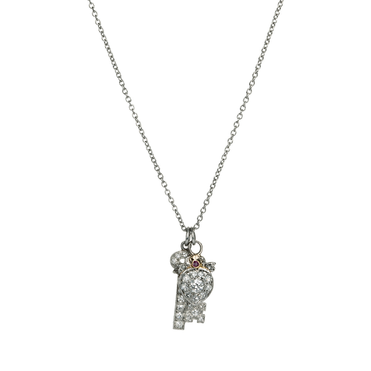 Diminutive Art Deco era ‘Key to my Heart’ charms on a platinum 18” cable link chain. A tiny heart crowned with a bow and ruby stone hanging with a matched key in platinum set with diamonds. Both pieces came from an early 20th-century charm bracelet. Continental European, 1930. Front view. 