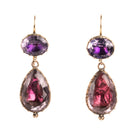 Lovely early 19th century earrings set in 15k gold. Cushion and pear shaped amethyst stones set in closed-back collet settings. The stones are a pale purple, with varied shades of purple and pink coming from the foil behind the stones. The coloring is very unique. English in origin. Circa 1800. Front view. 