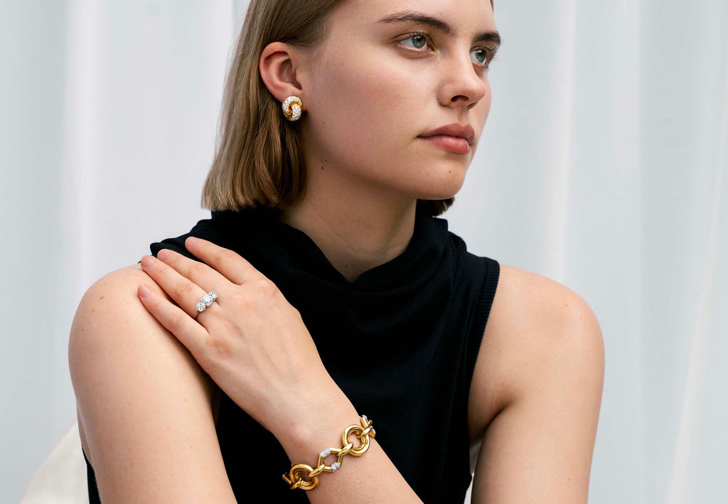 Vintage pave diamond knot earrings. Timeless ear clips in 18k gold. The intertwined loop design is set with approximately 4.50 carats in total diamond weight. The diamonds are estimated to be G to H in color, and VS1 to VS2 clarity. America, circa 1980. On a model. 
