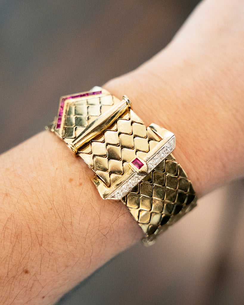 Mid-century gold buckle bracelet with rubies and diamonds in 18k gold. The functional buckle design has an adjustable fit. American in origin. Circa 1940. Worn on a model. 