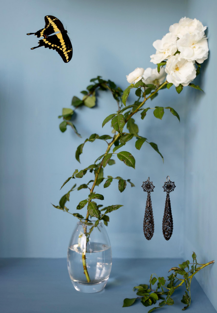 Berlin iron torpedo earrings. Gothic pattern in elongated oversized pendeloque shapes. German in origin. Circa 1820. A still life view with a butterfly and flower. 
